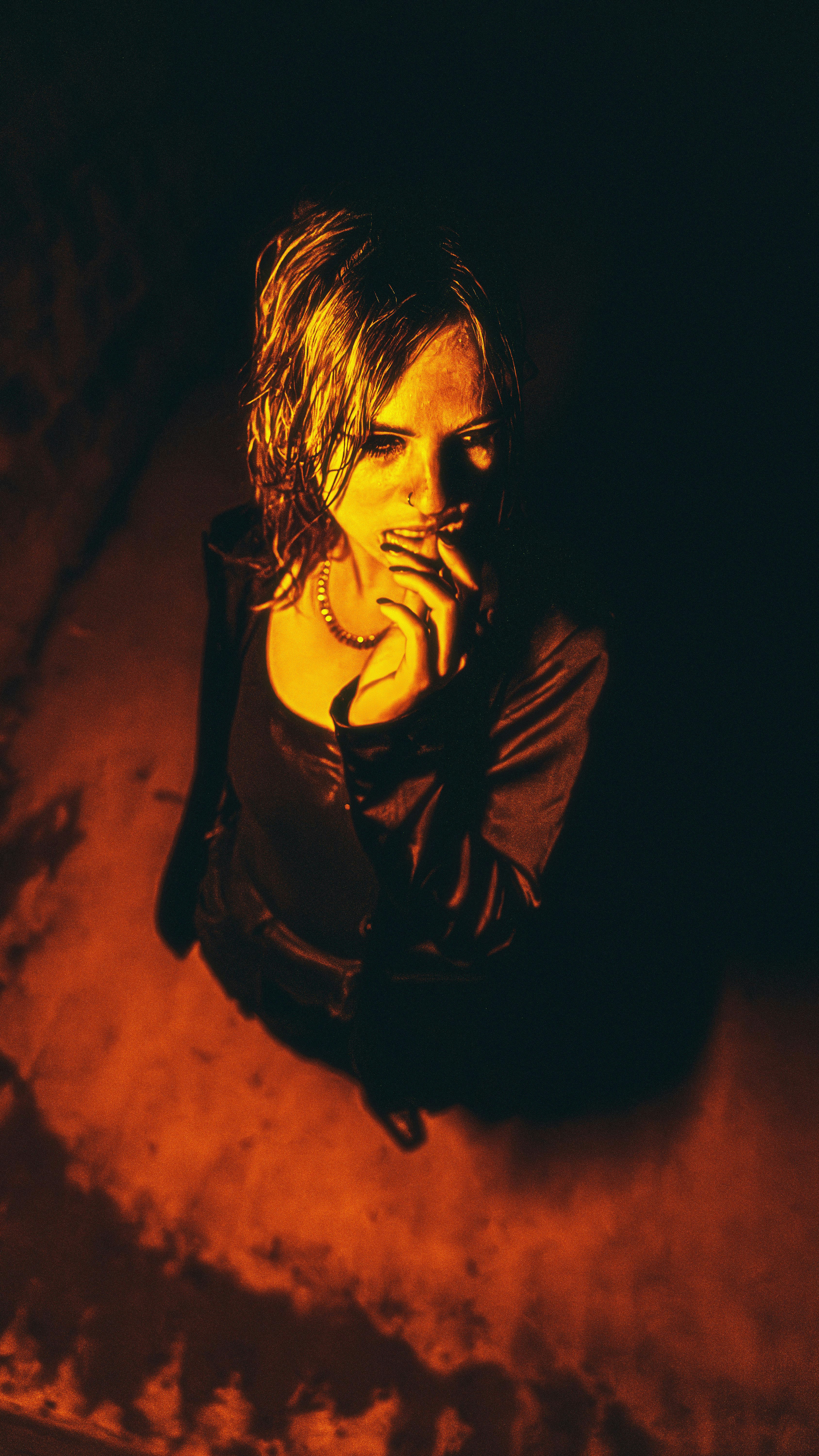 A woman looks thoughtful in a dimly lit space.