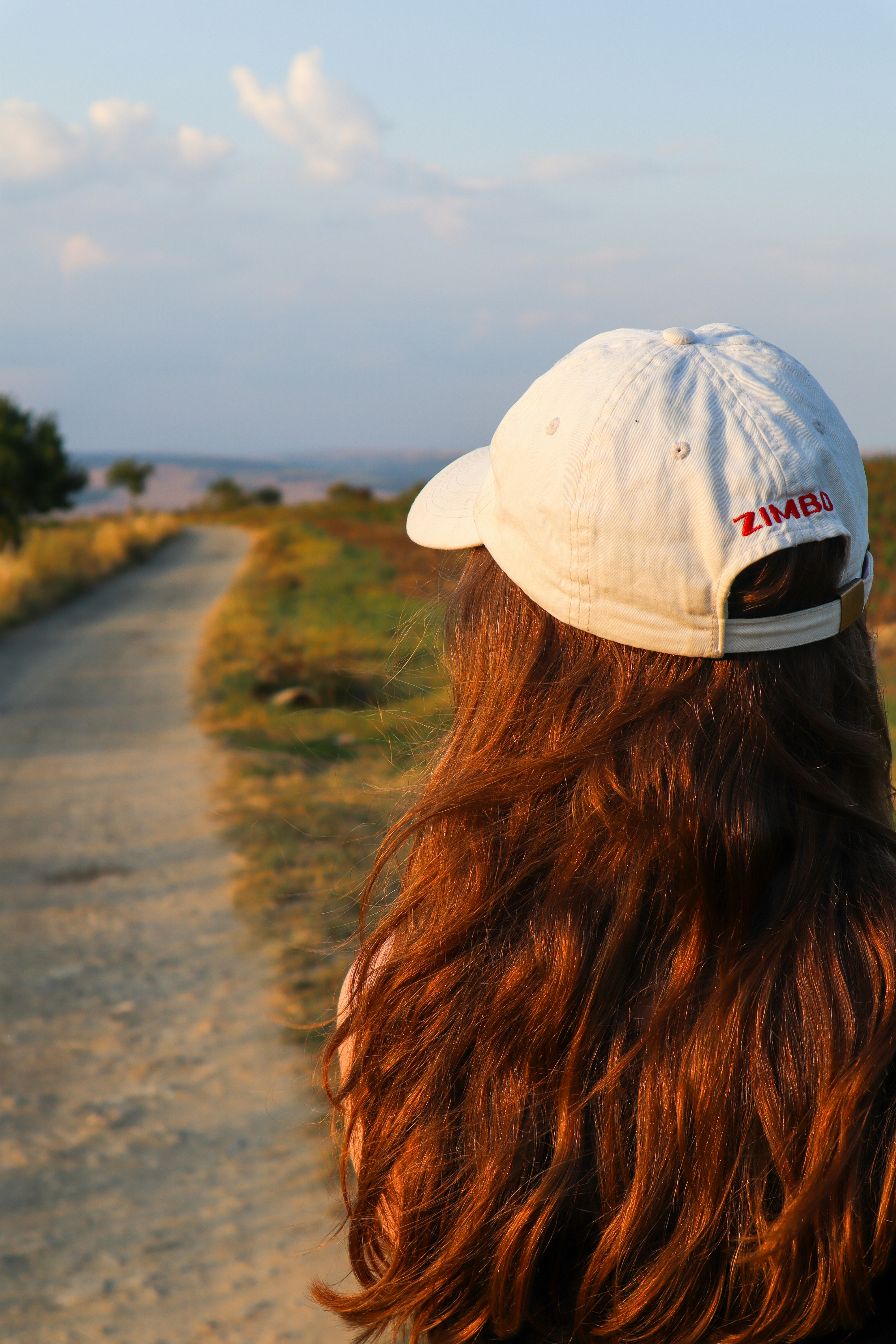 Woman with long hair looks down a dirt path.
