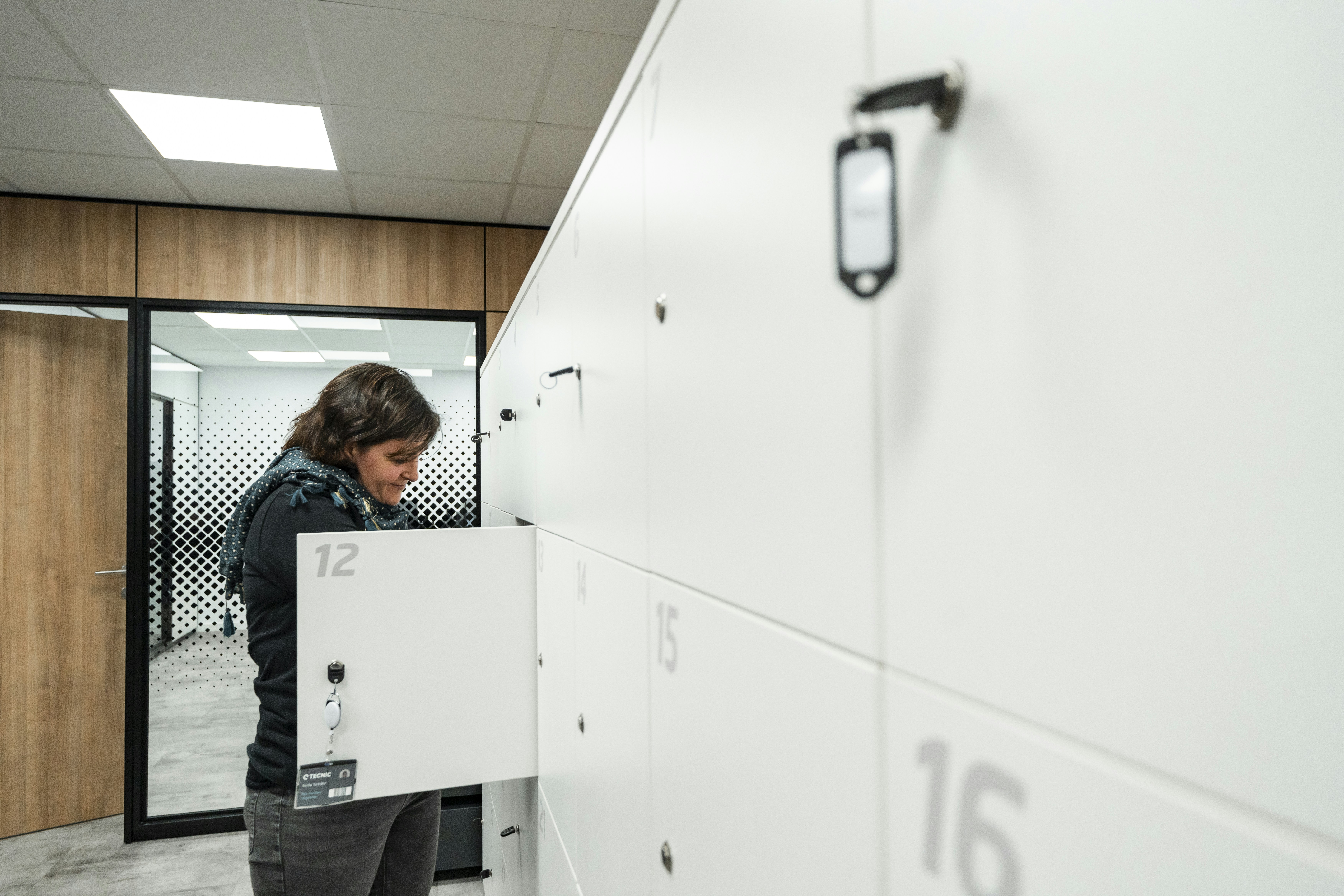 A woman is opening a locker in the hallway.