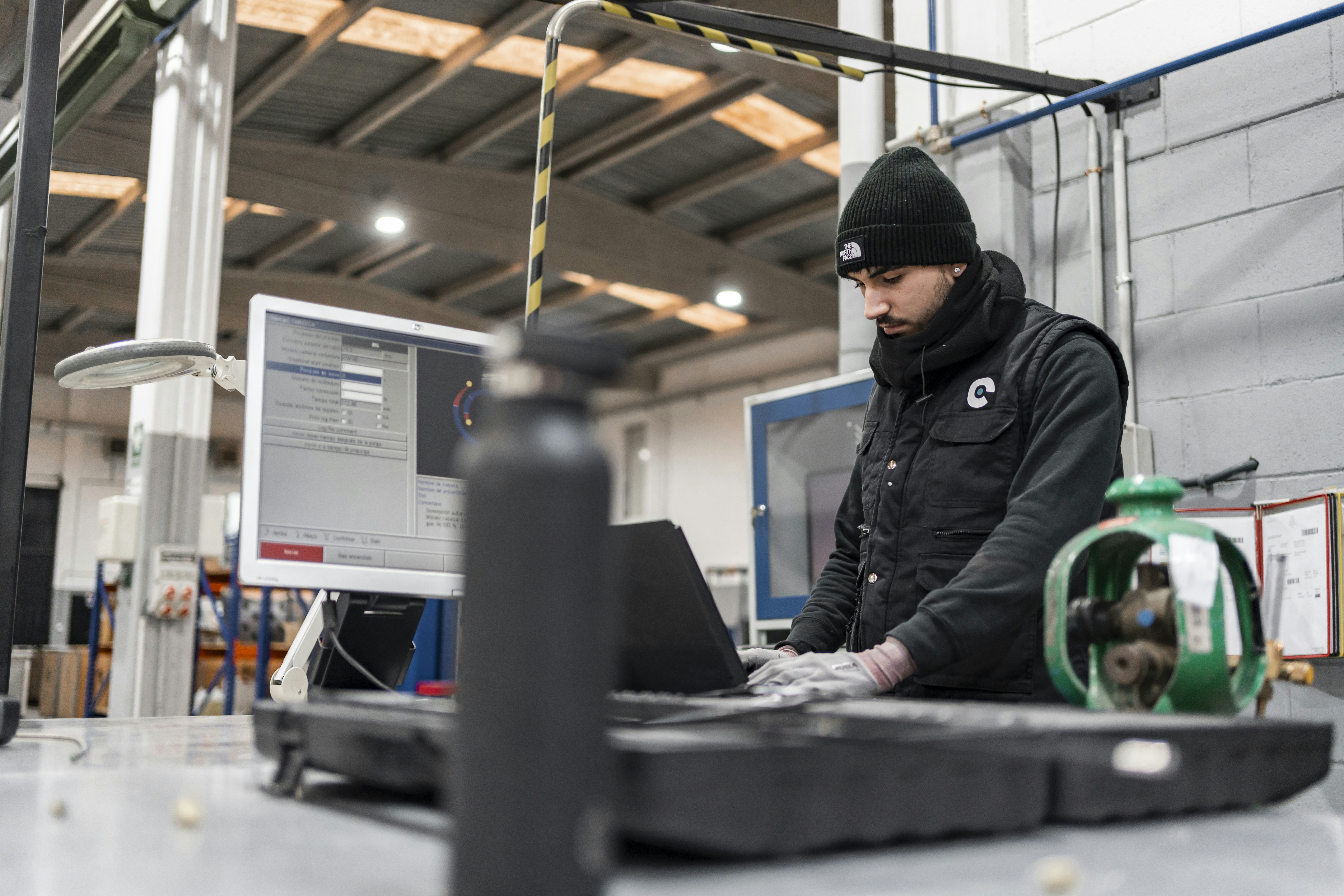 Man works on a computer in a manufacturing setting.