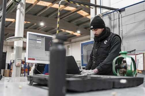 Man works on a computer in a manufacturing setting.