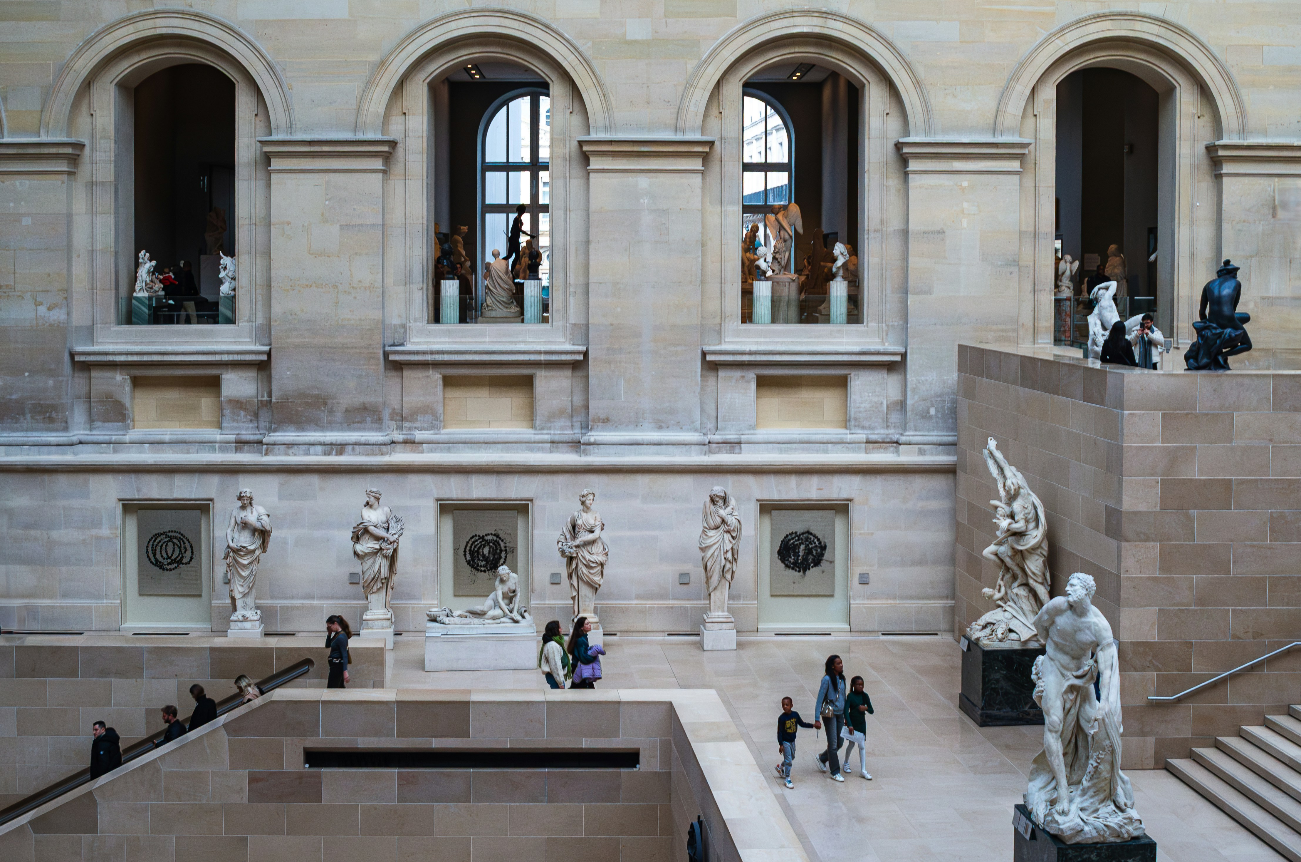 Museum atrium with statues and open windows.