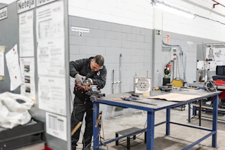 A worker is grinding metal in a workshop.