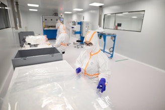 Workers in protective suits inside a cleanroom.