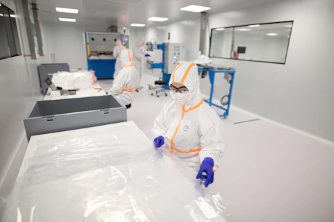 Workers in full protective suits in aerospace cleanroom