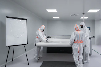 Workers in protective suits work in a cleanroom.