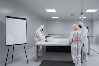Workers in protective suits work in a cleanroom.
