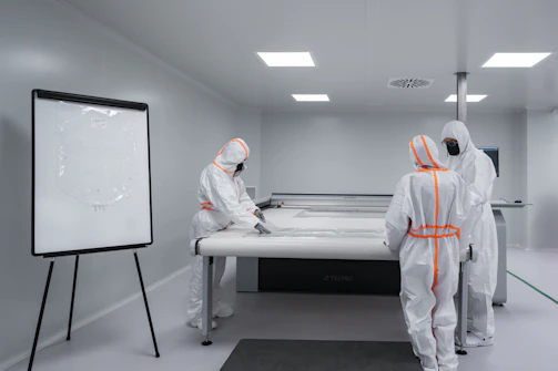 Workers in protective suits work in a cleanroom.