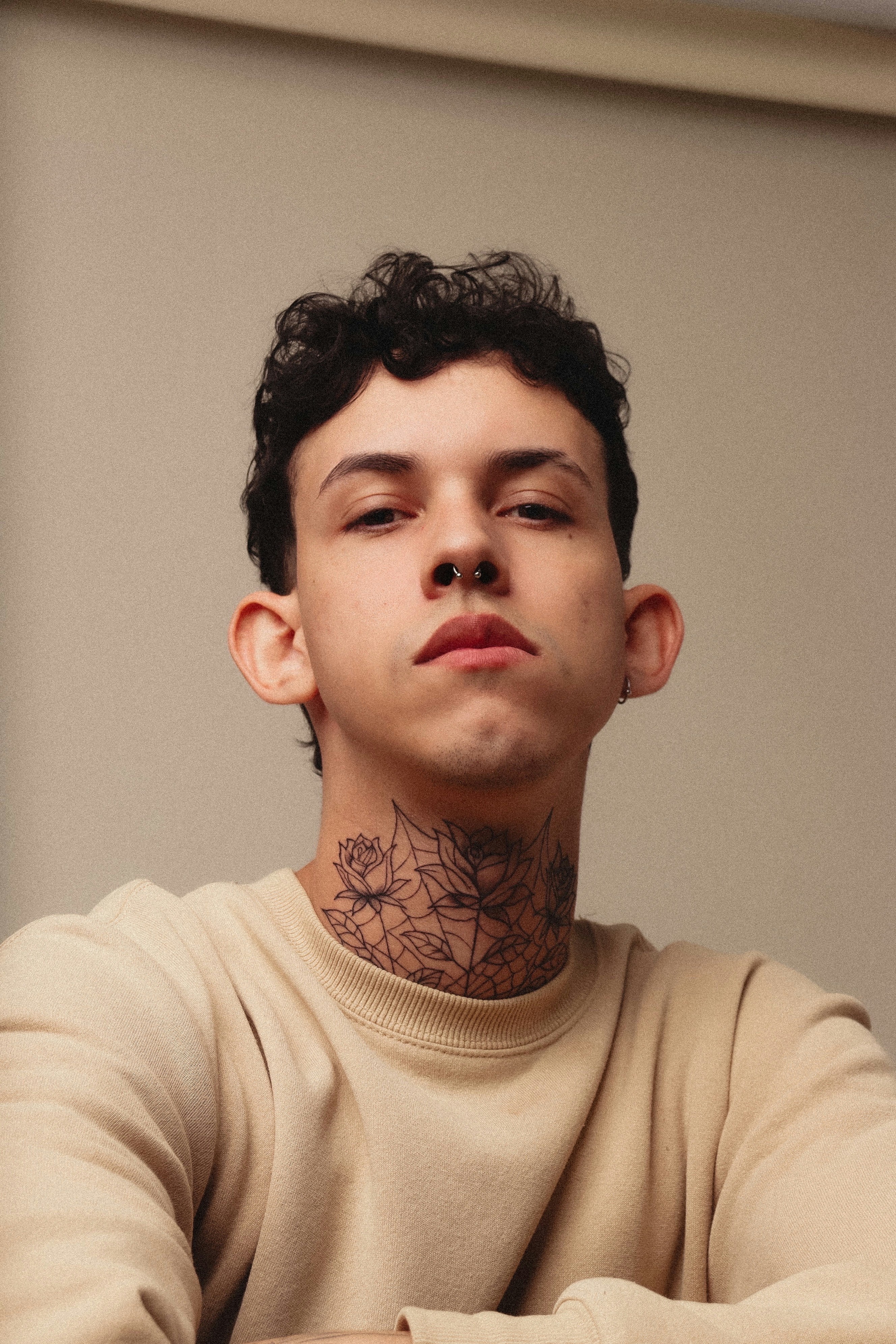 Young person with tattoos gazes directly at the camera.