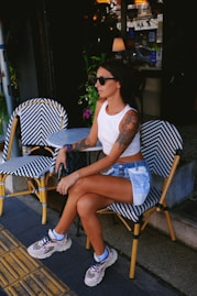A woman sits outside a cafe, relaxed and stylish.