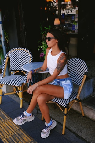 A woman sits outside a cafe, relaxed and stylish.