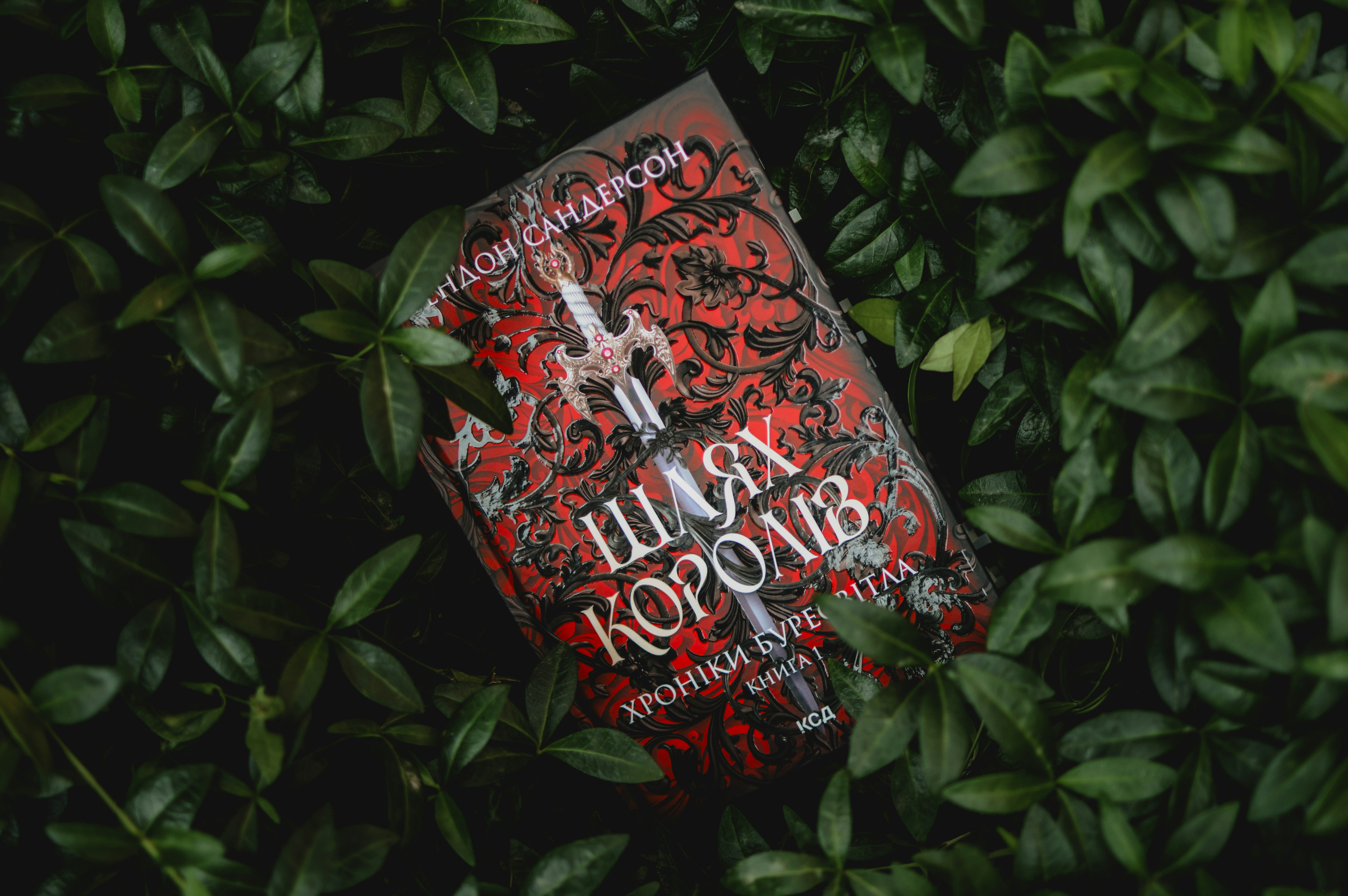 A book lies amidst green foliage.