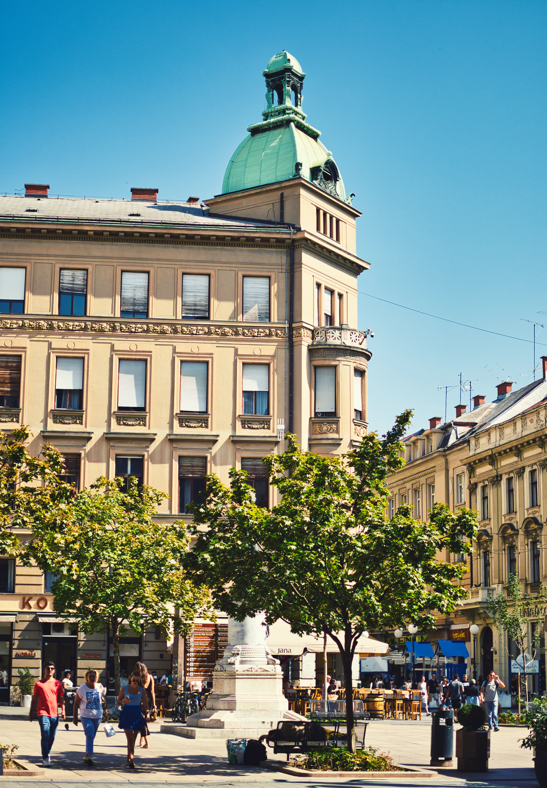 A sunny square framed by trees and buildings in Zagreb
