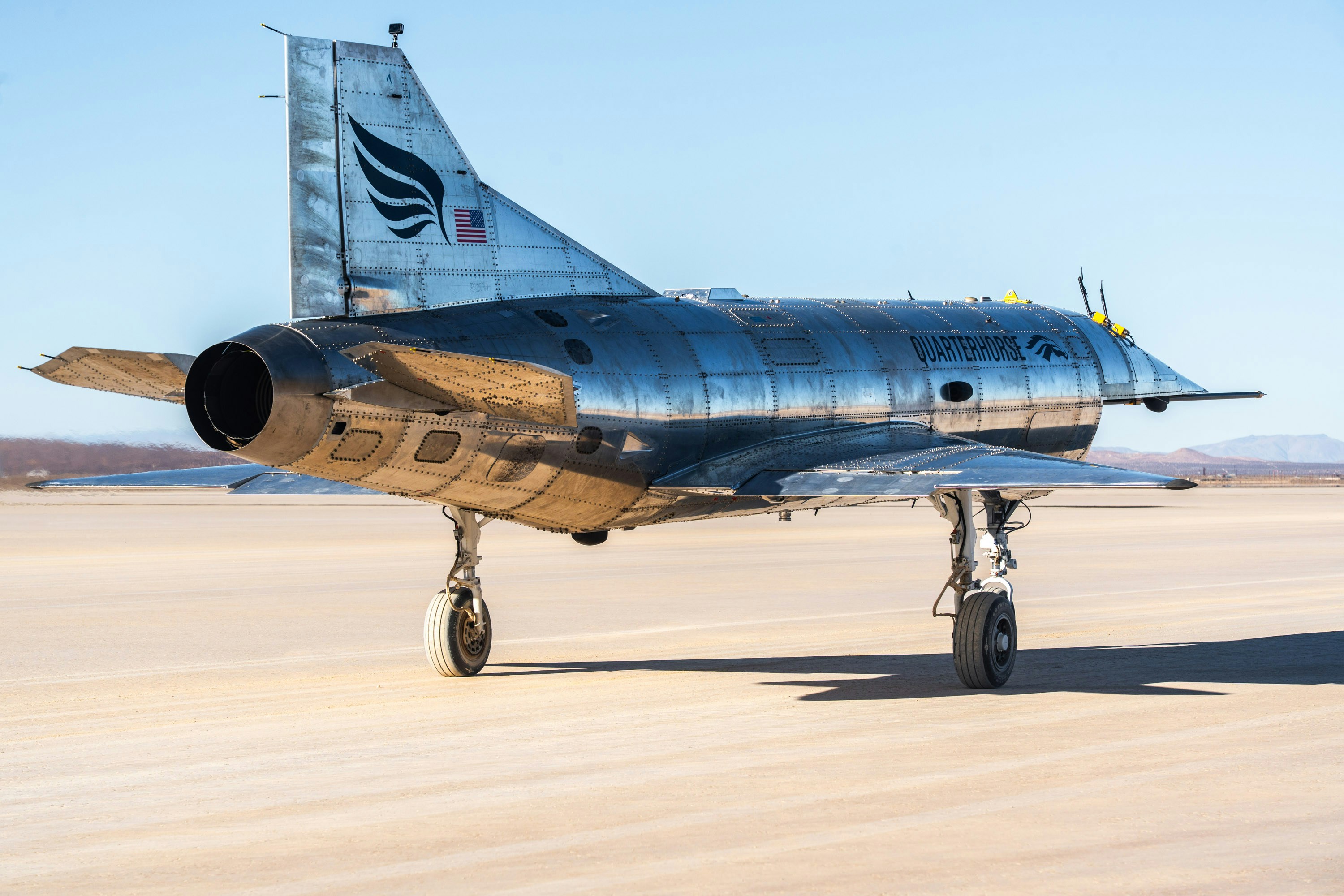 A shiny jet aircraft is on a desert plane.