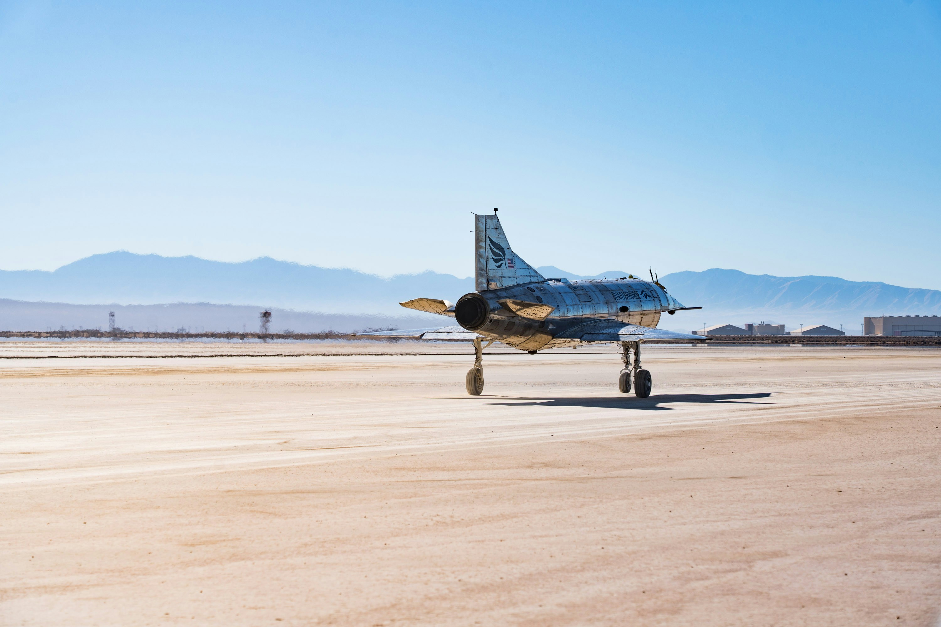 A fighter jet sits on a desert runway.
