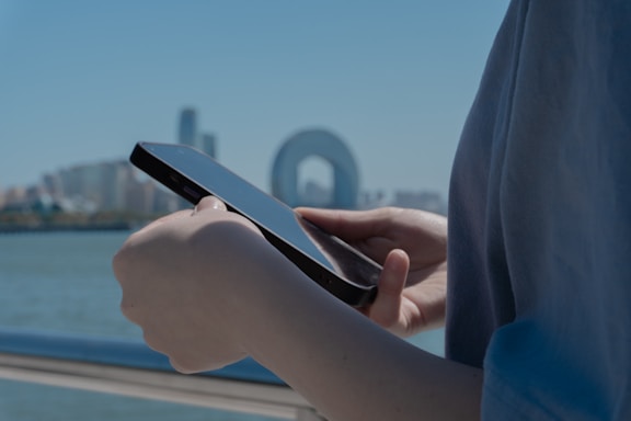 Person holds a phone against a city backdrop.