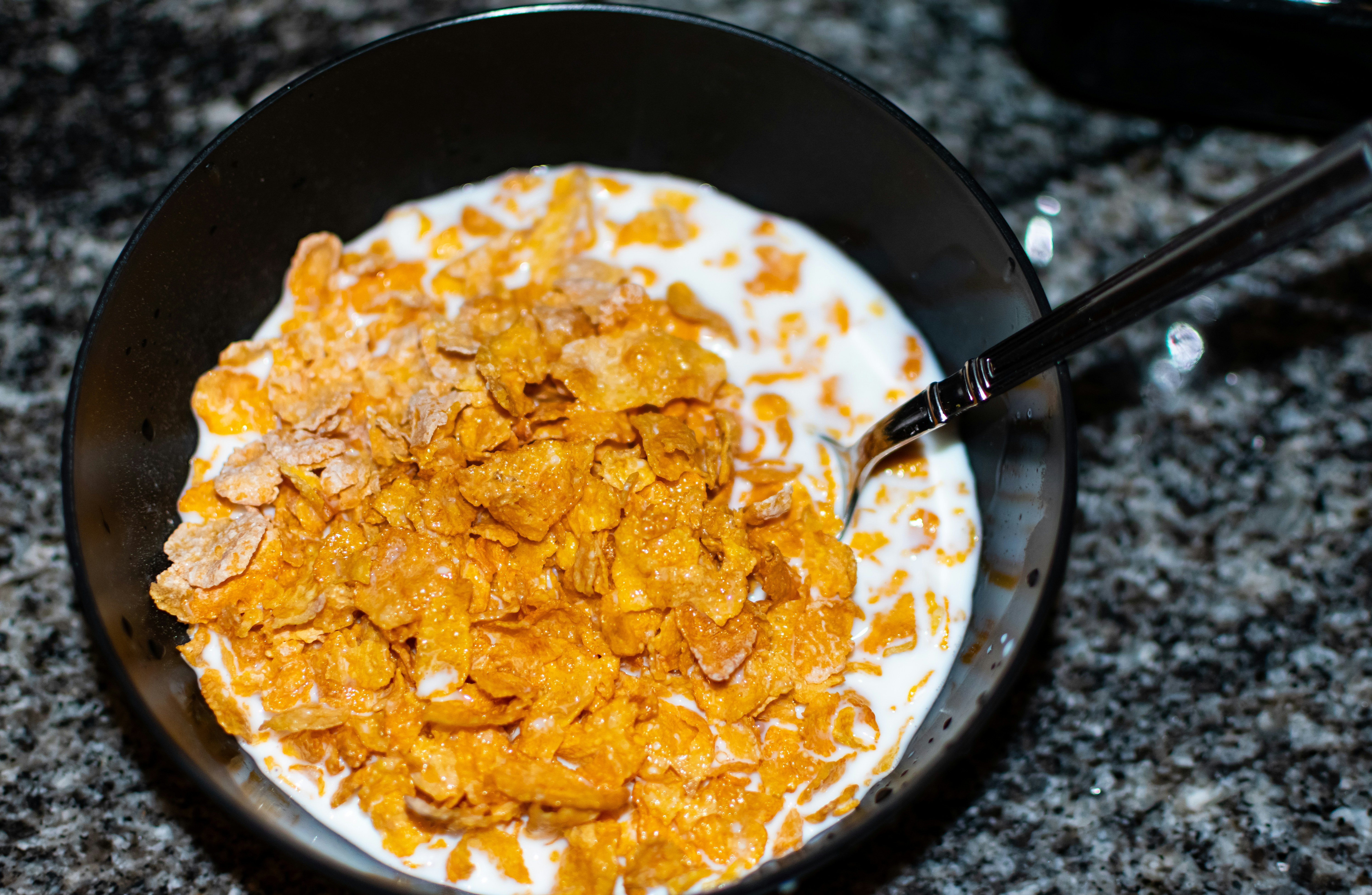 Cornflakes and milk sit in a bowl.