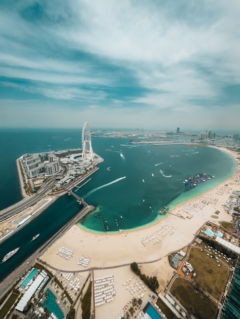 Aerial view of Dubai's coastline and dense skyline of high-rise towers under clear sky.