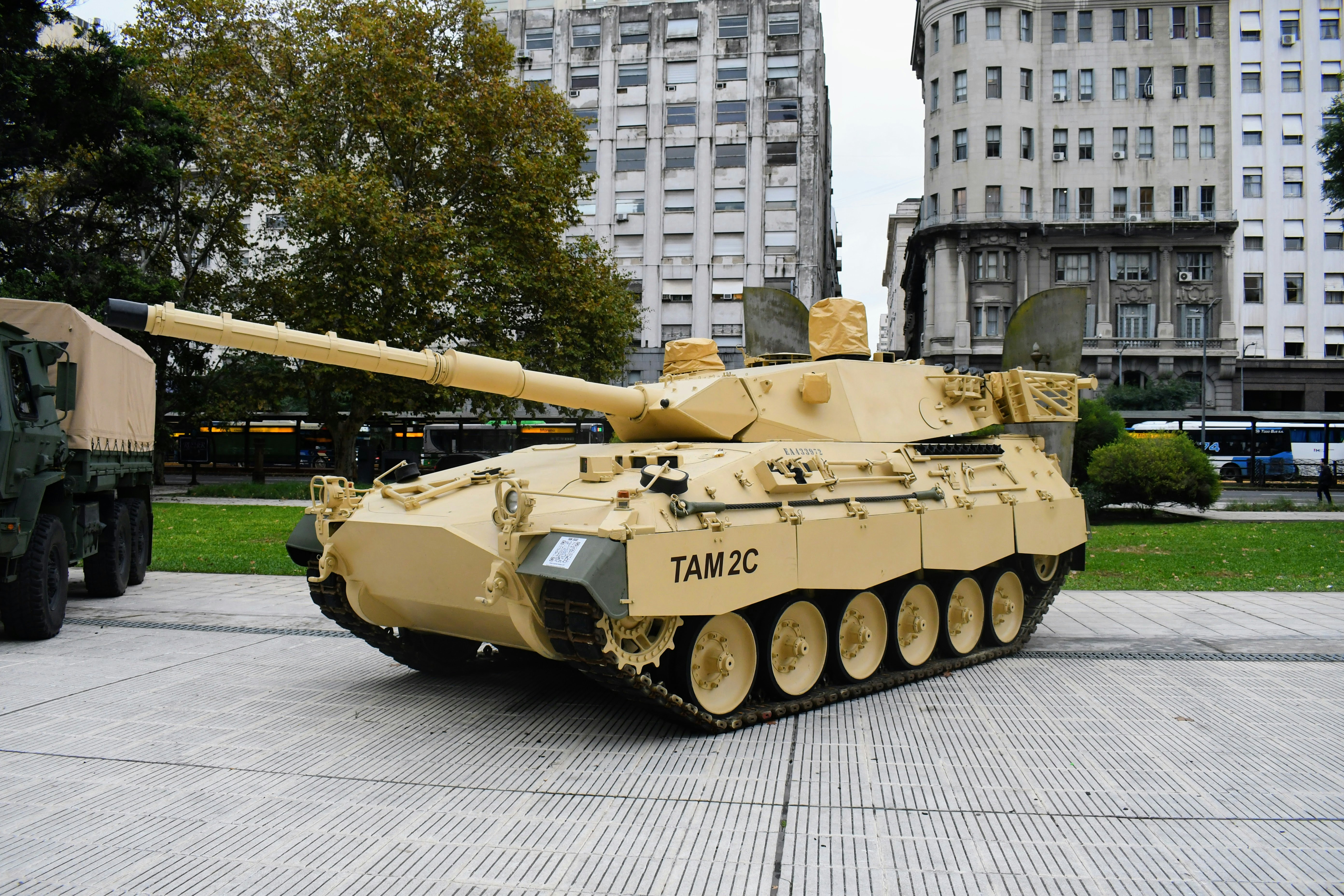 A tan tank is parked on a city street.
