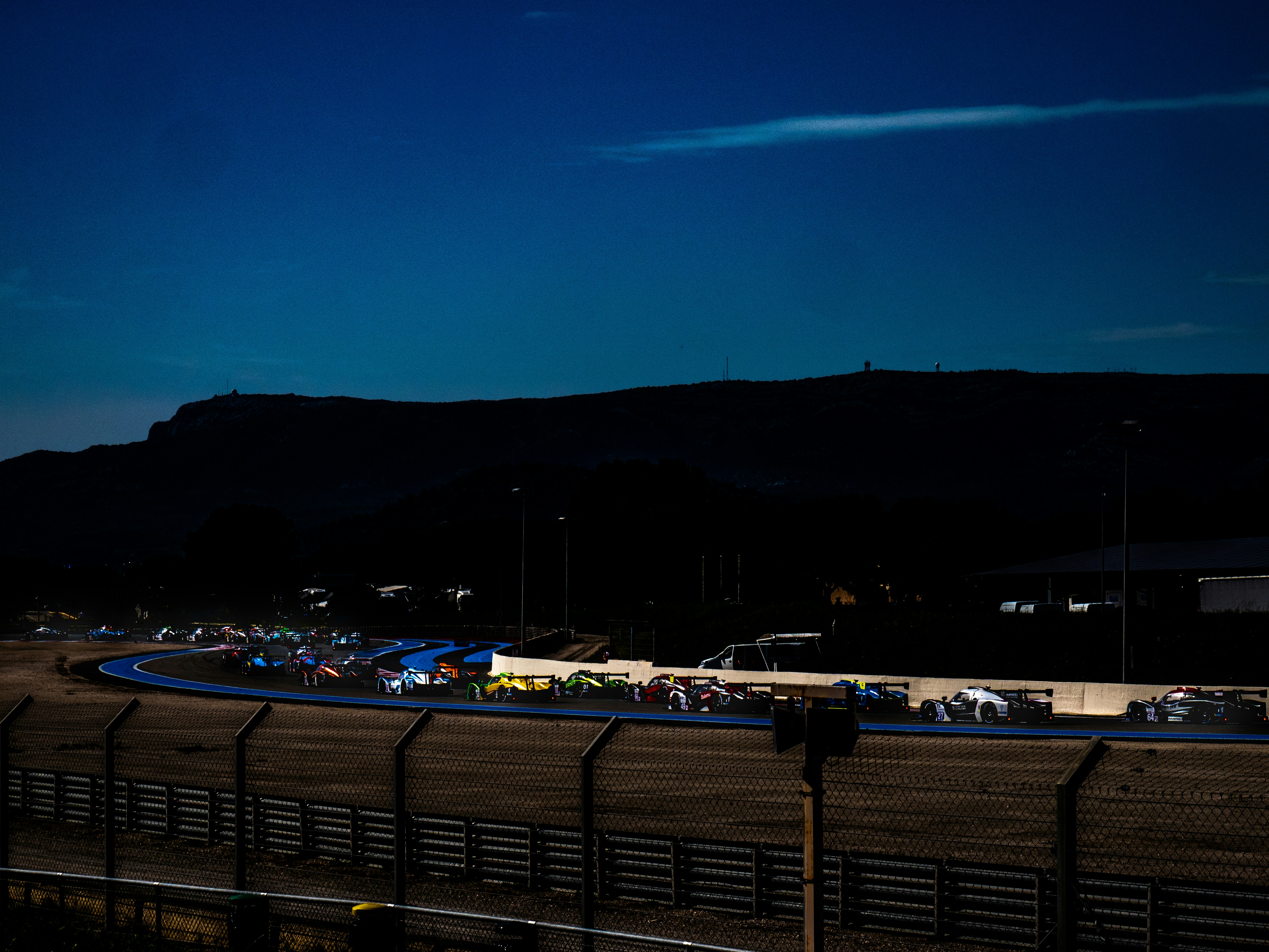 Les voitures font la course sur une piste au crépuscule