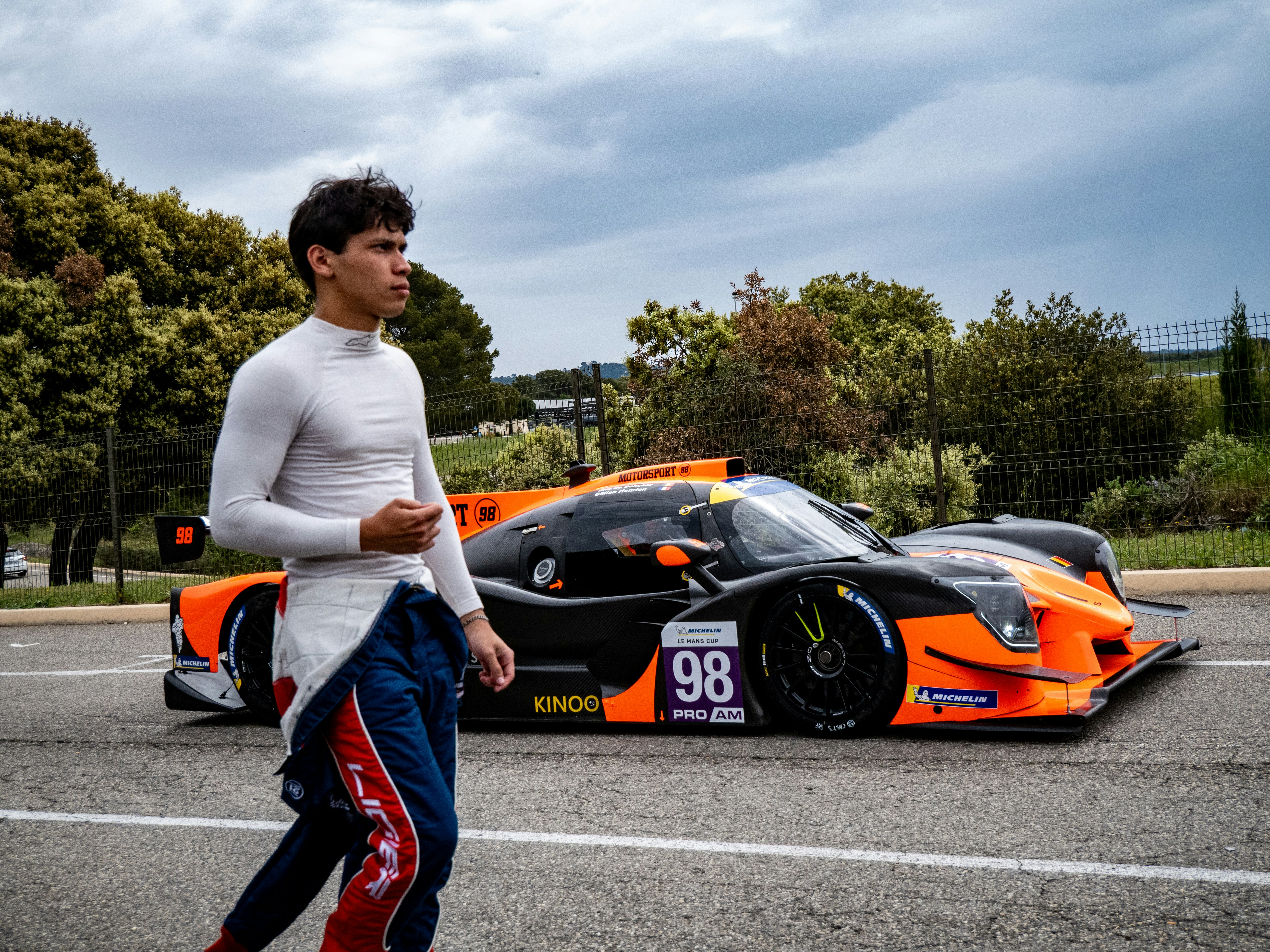 Un pilota passa davanti alla sua auto da corsa.