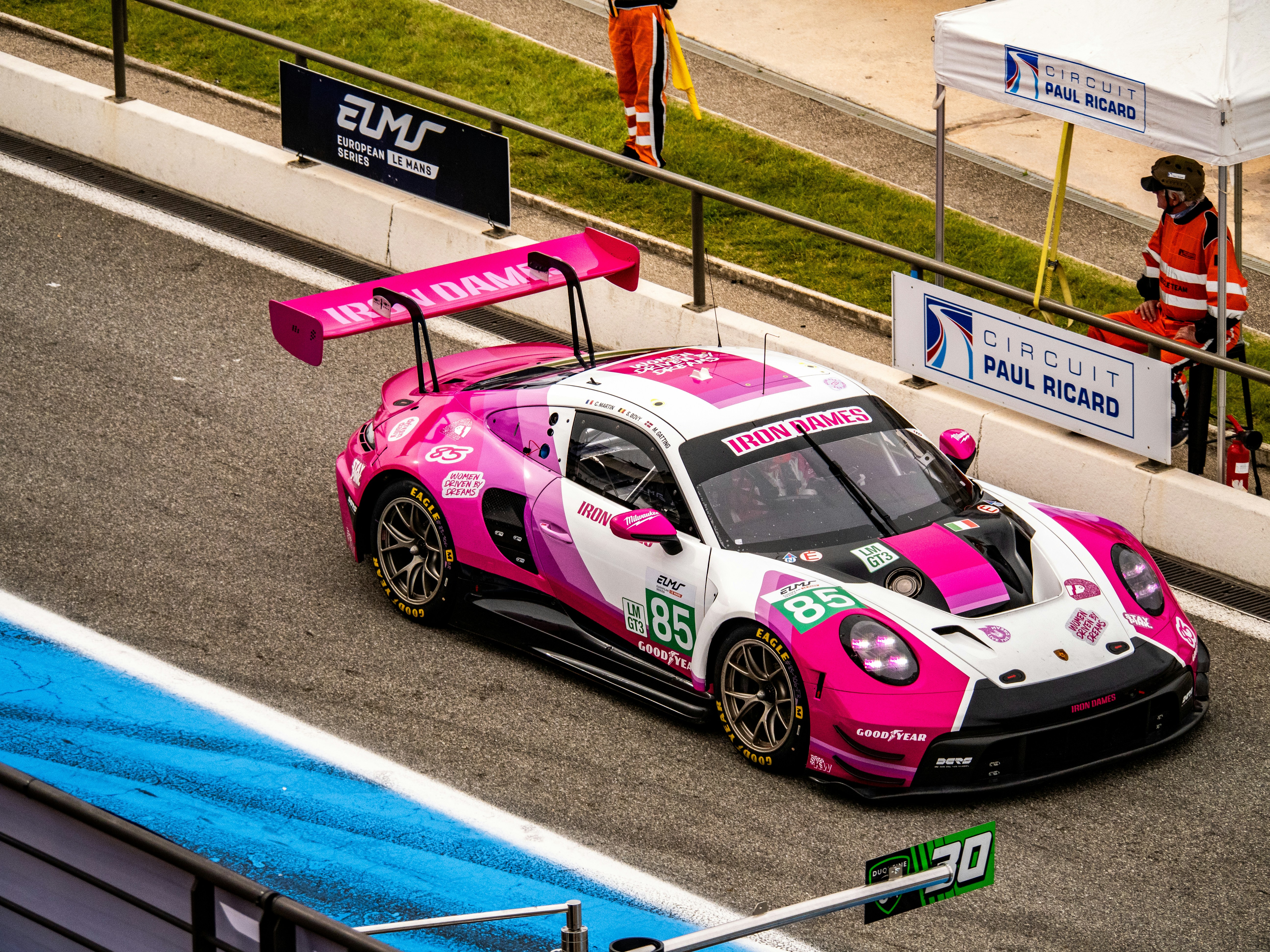 Un'auto da corsa rosa sfreccia su una pista da corsa.