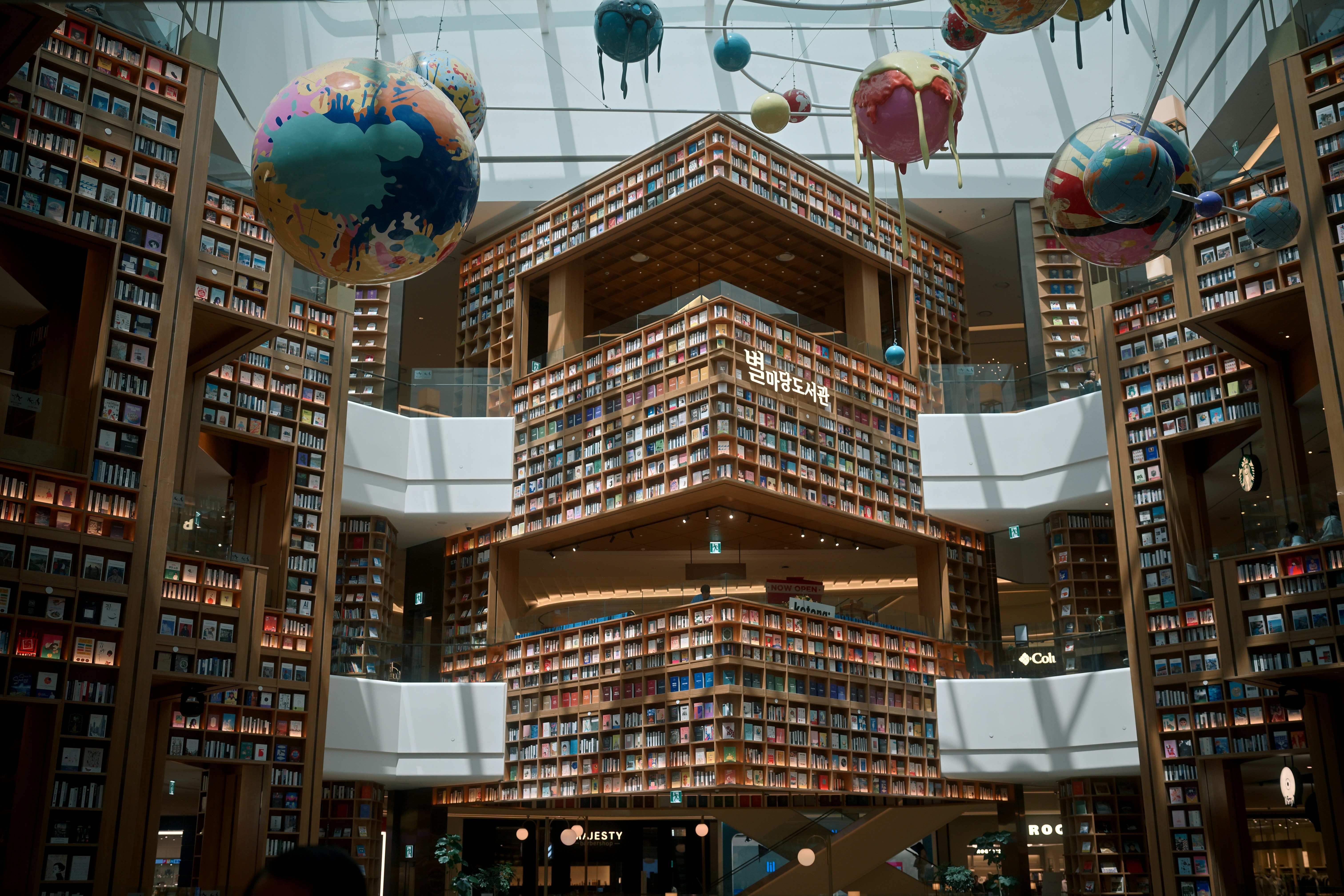 A grand, historic library with towering wooden bookshelves bathed in natural light, showcasing intricate architectural details.