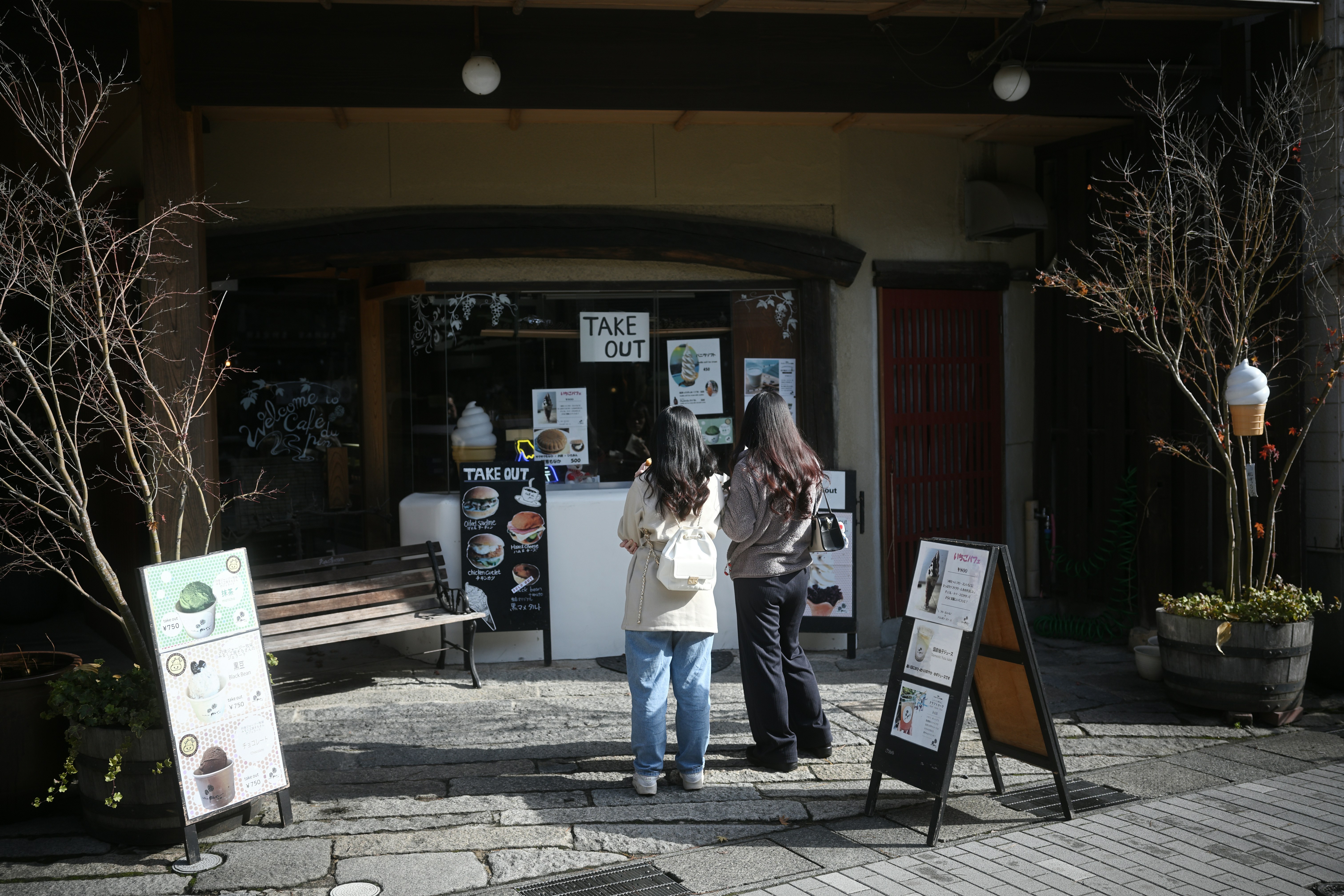 Two people stand in front of a cafe entrance.