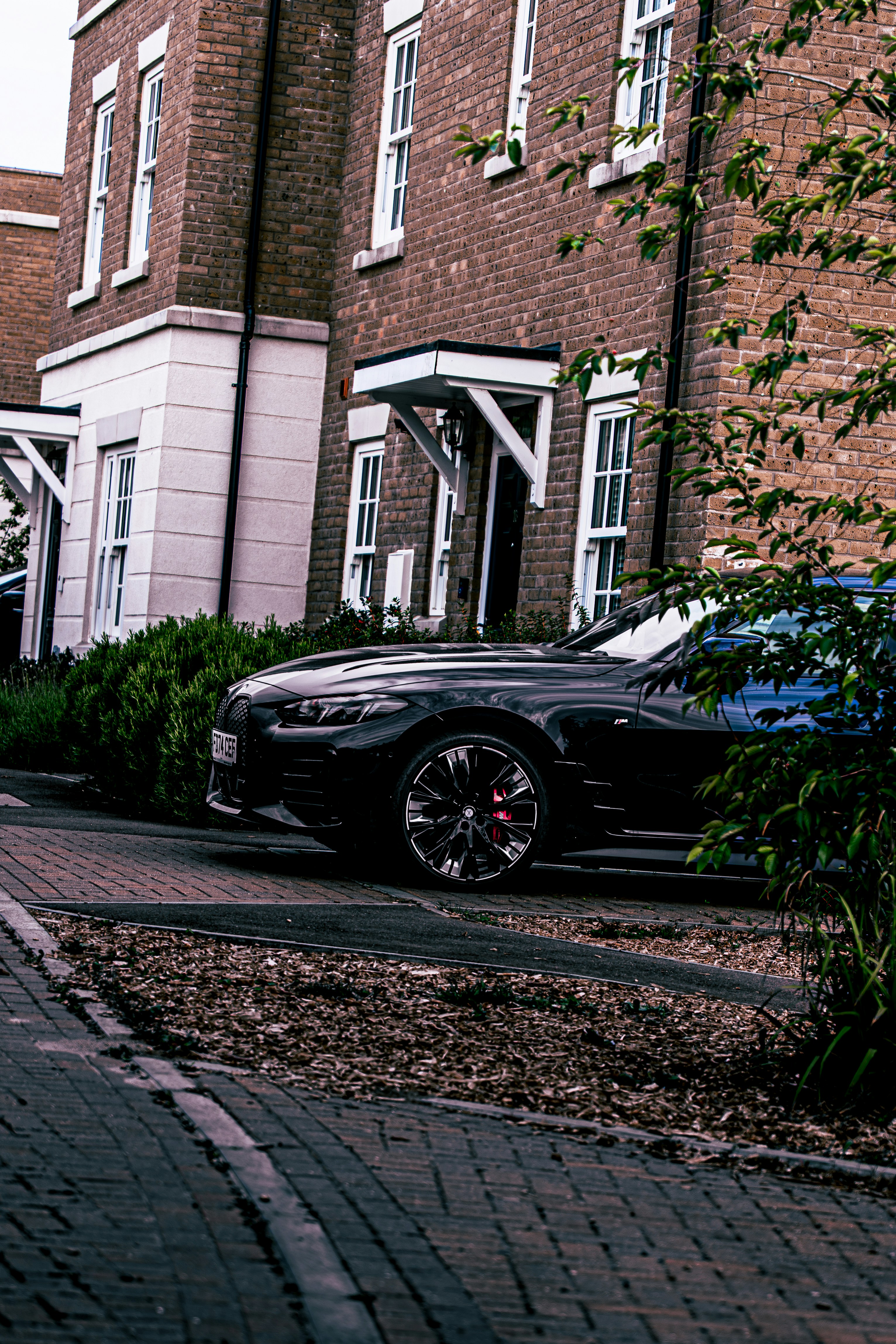 A sleek black car is parked in front of a house.