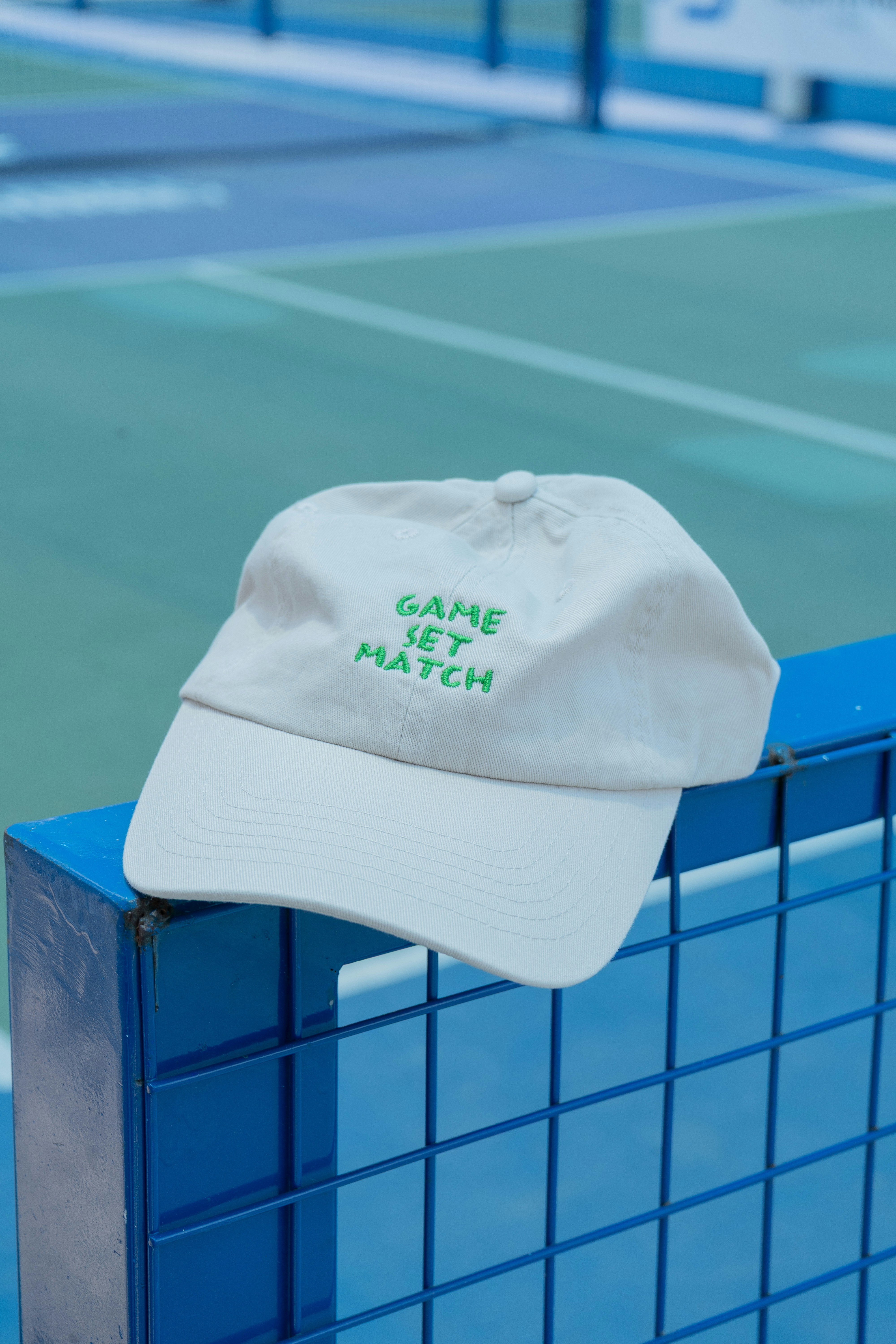Ein Tennishut ruhte auf dem blauen Zaun des Platzes.