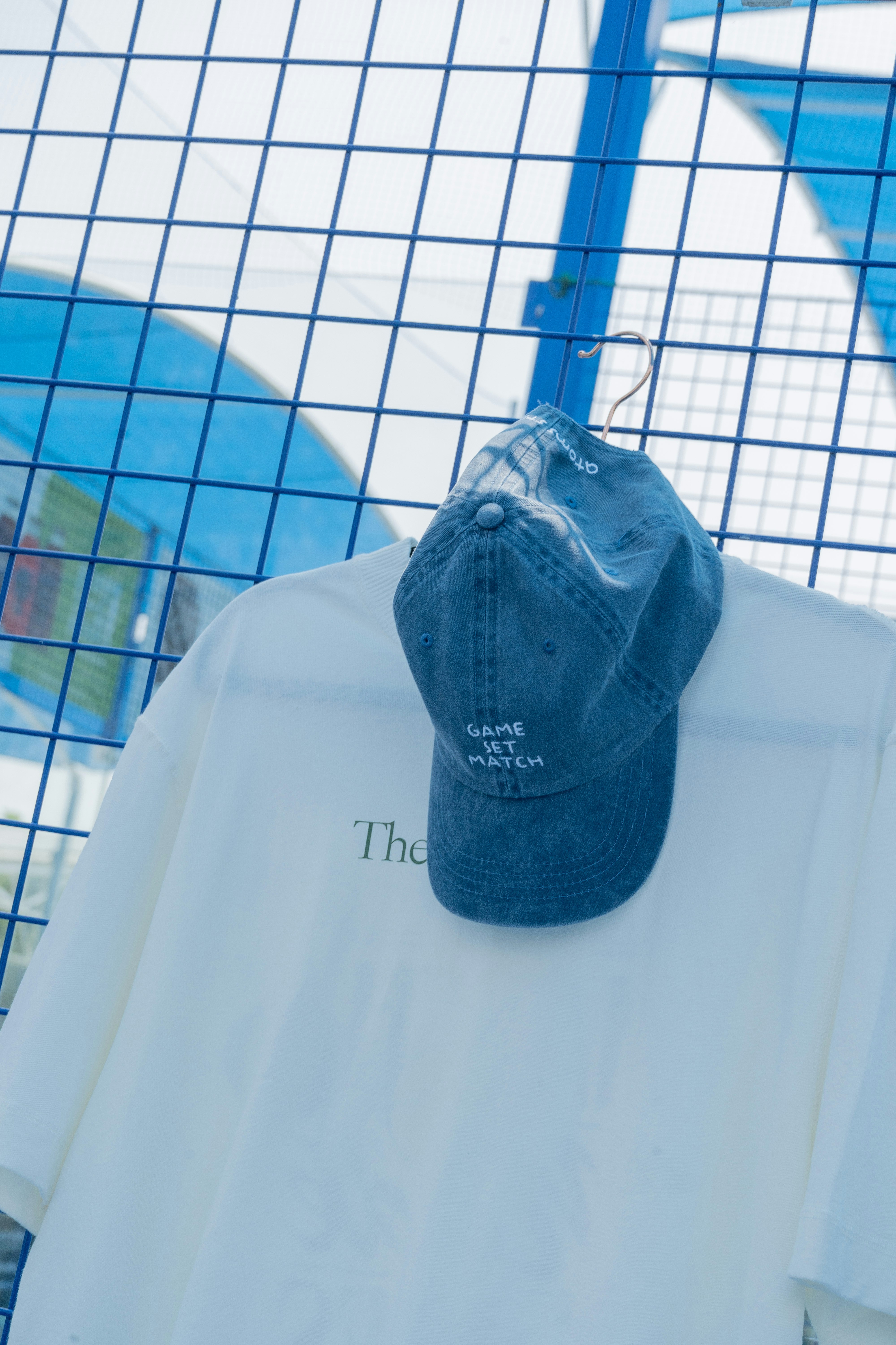Ein weißes T-Shirt und eine blaue Mütze hängen.