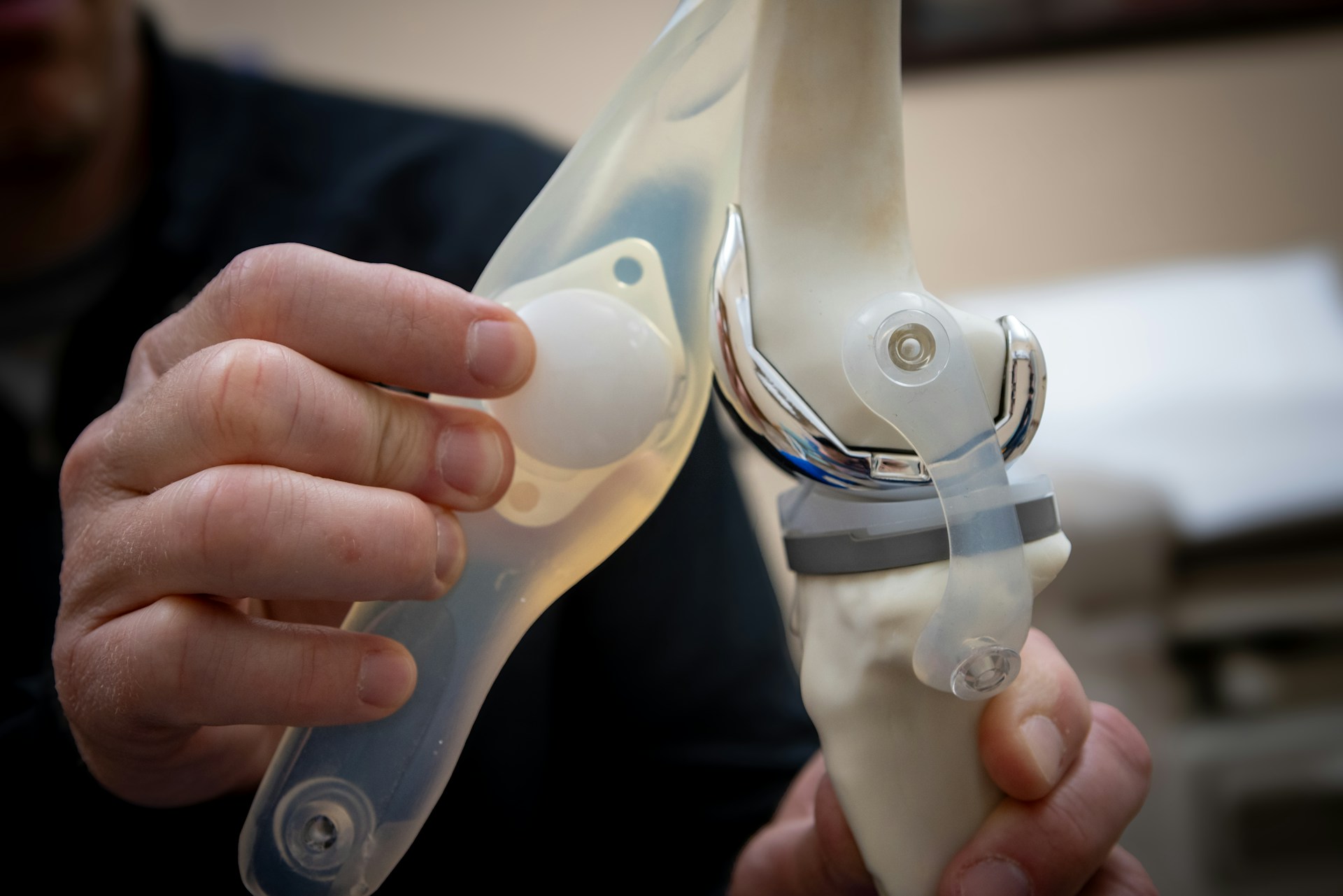 Man examines a knee joint model.