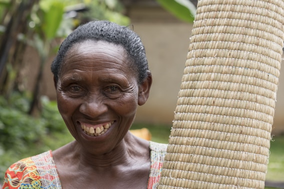 A woman smiles holding woven crafts.