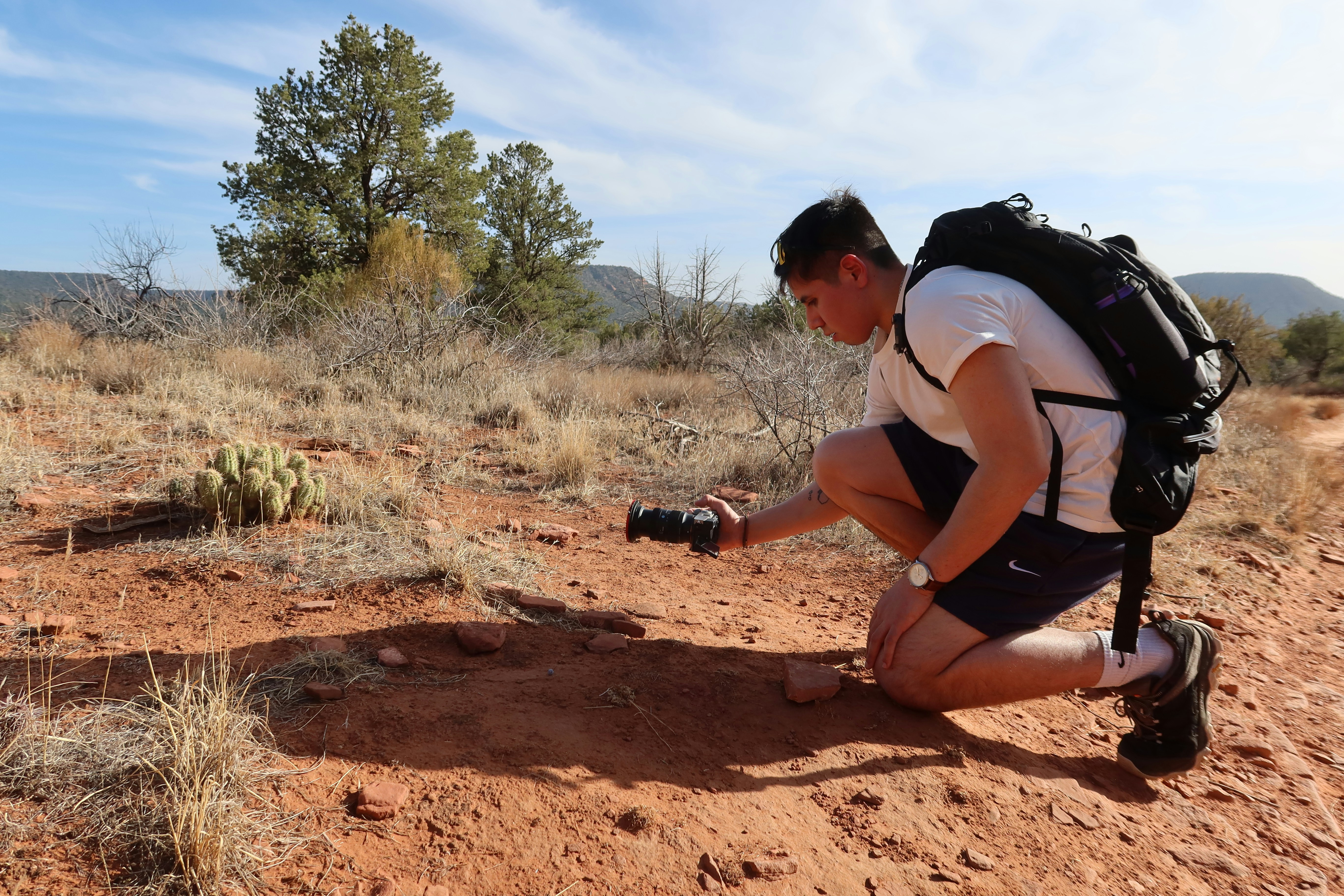 A hiker studies something on the ground.