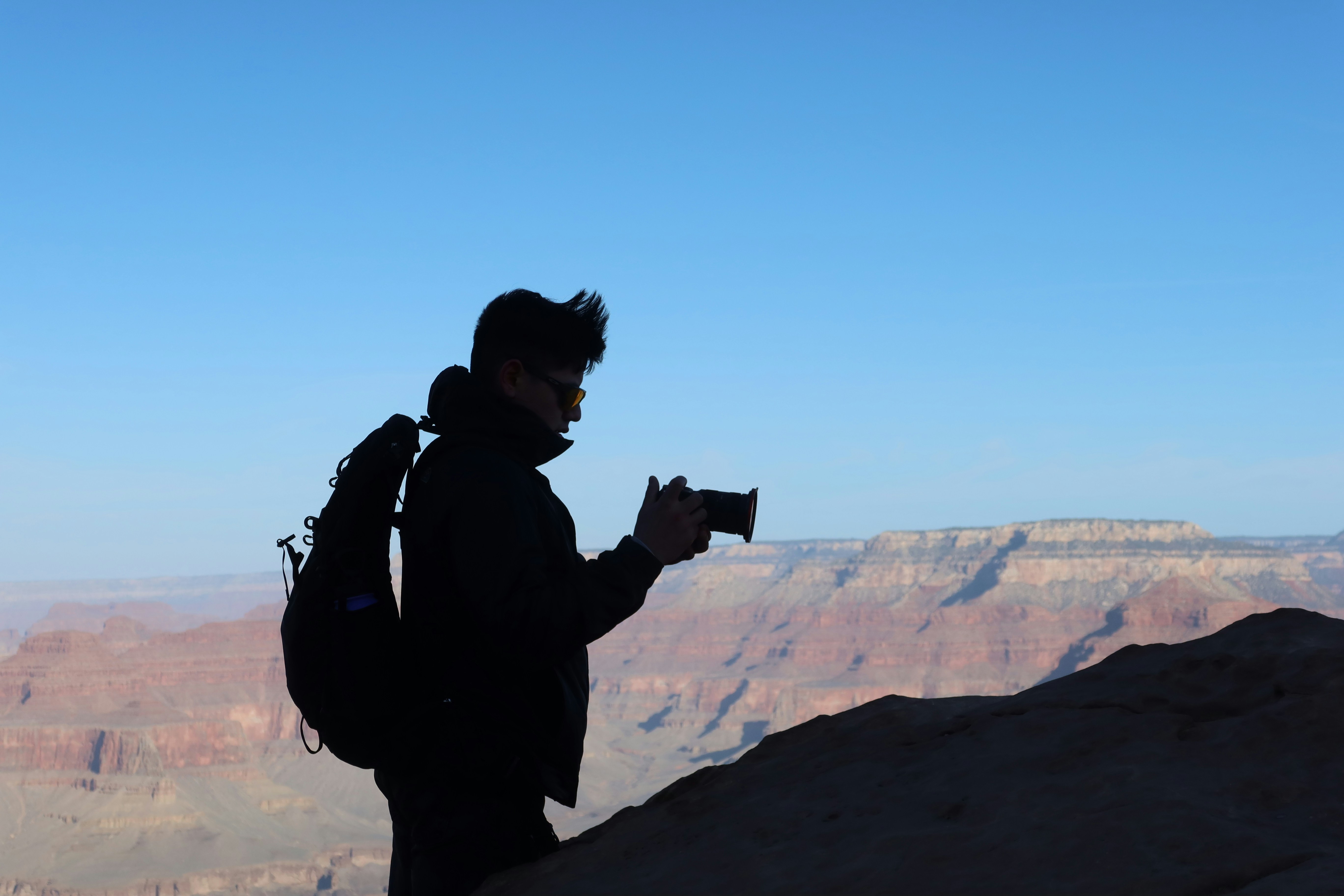 A traveler using a compact point-and-shoot camera to capture a scenic landscape - cheap travel camera
