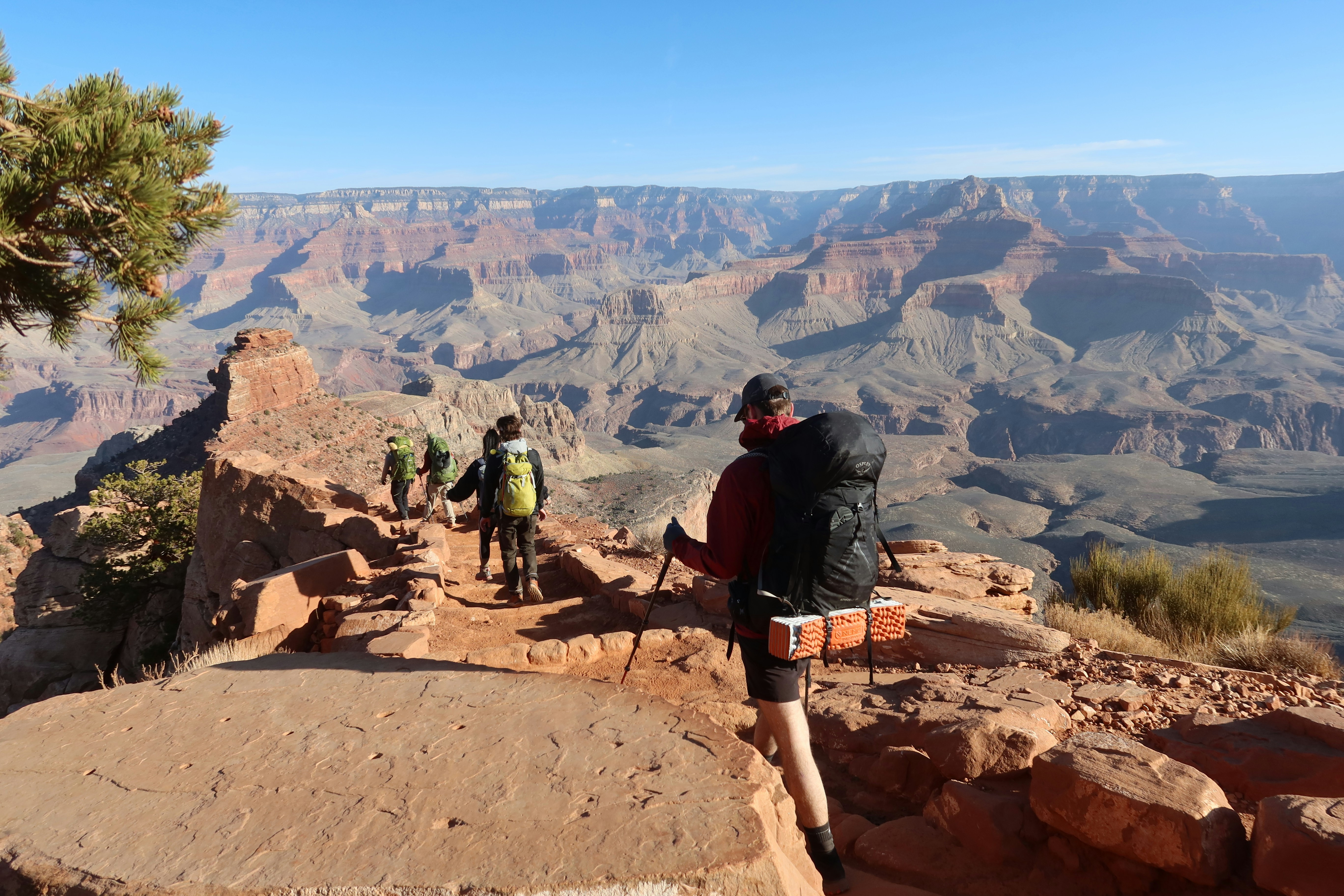 Hikers enjoying panoramic views from a rocky overlook above the South Rim of Grand Canyon National Park.