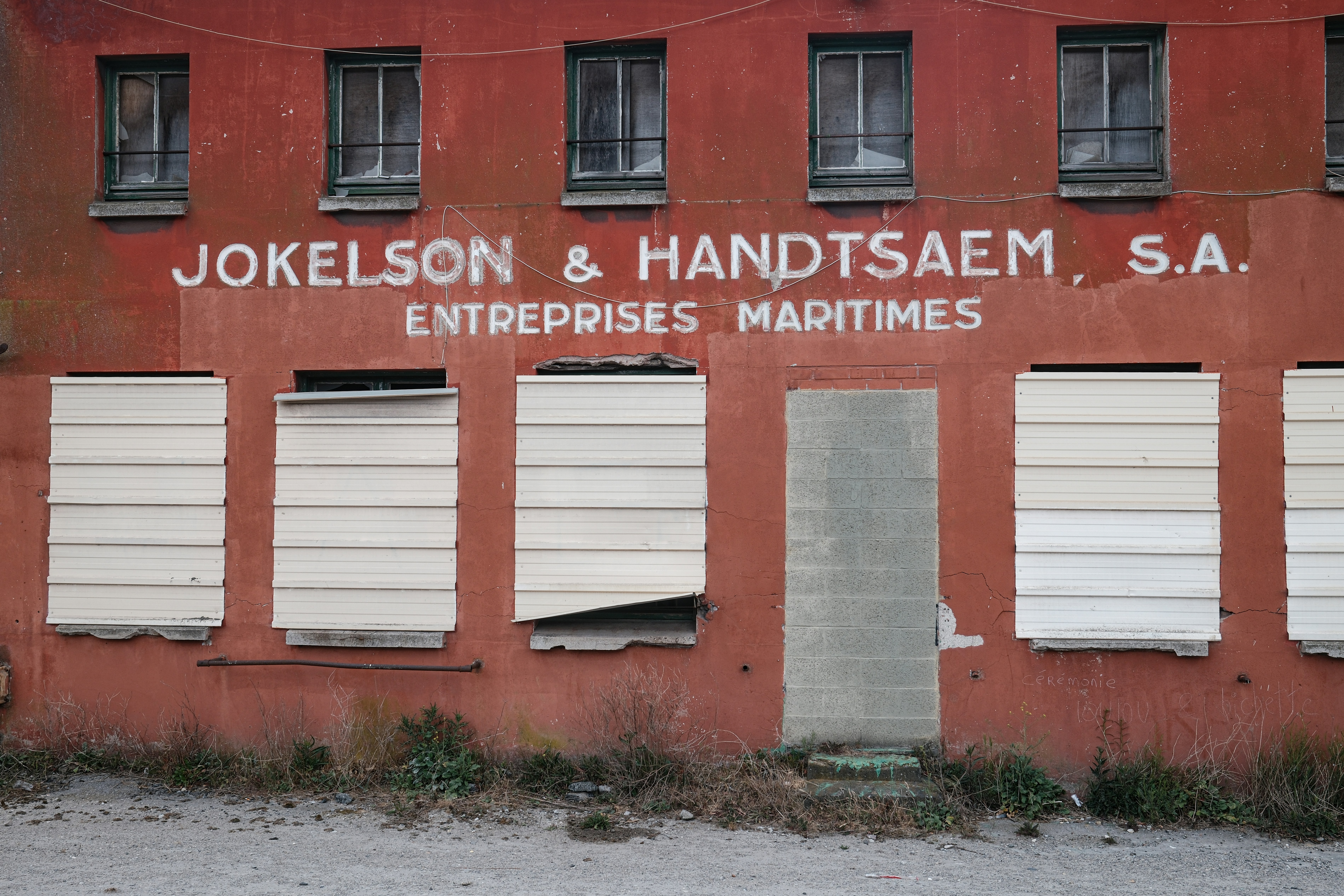 Old building with boarded-up windows and faded signage.