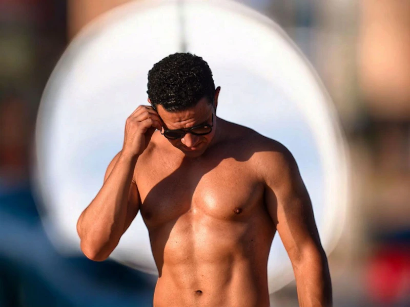 Shirtless man adjusting sunglasses, confident and stylish