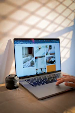 A laptop displays photos while a hand uses it.