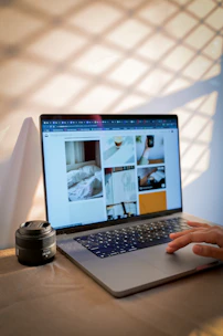 A laptop displays photos while a hand uses it.