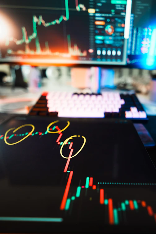 Stock market charts are displayed on digital devices.