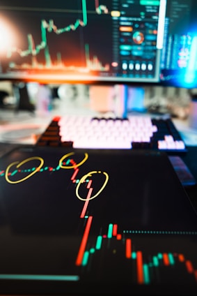 Stock market charts are displayed on digital devices.