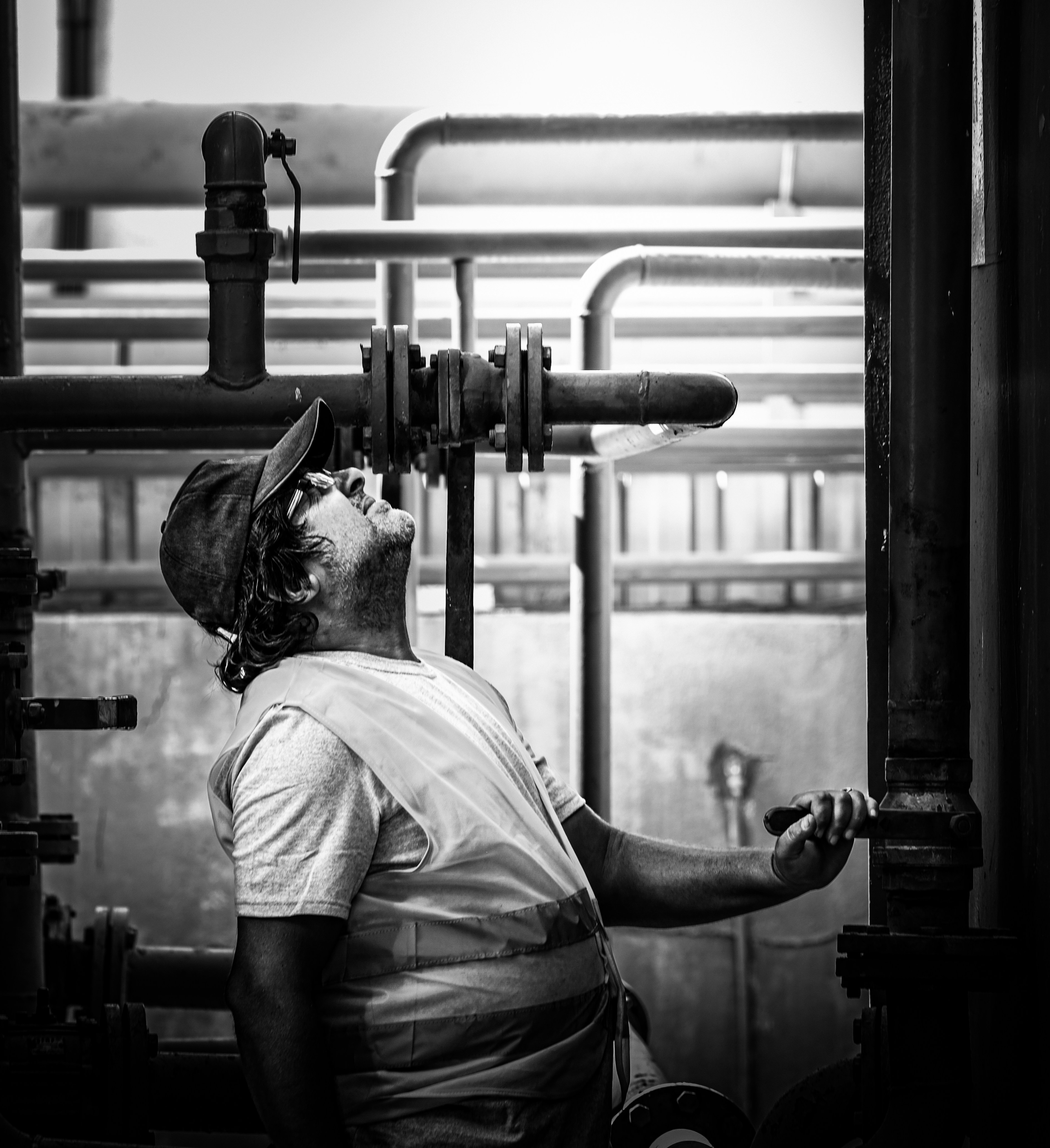 A worker inspects industrial pipes and valves.