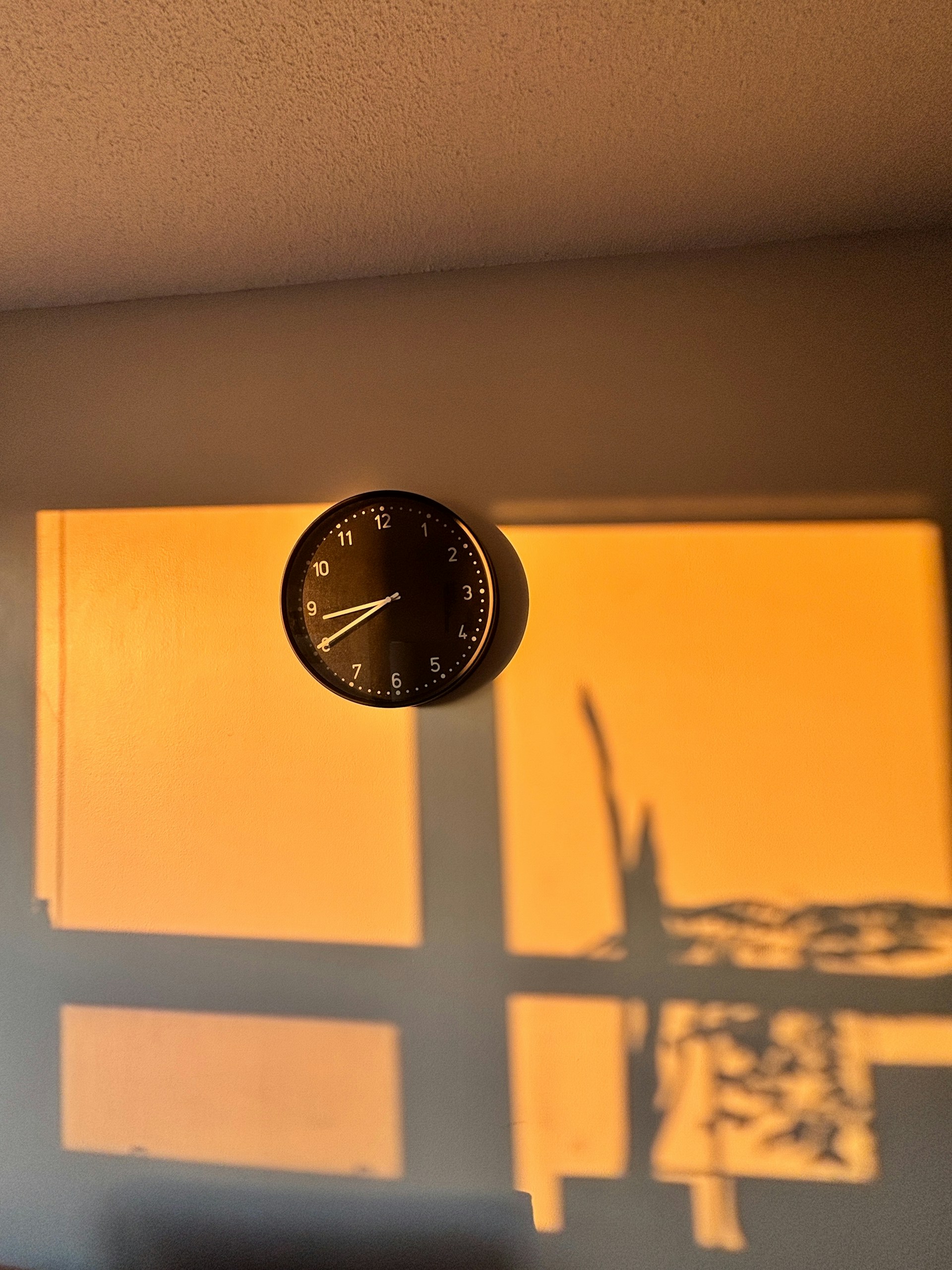 A clock hangs on a glowing orange wall.