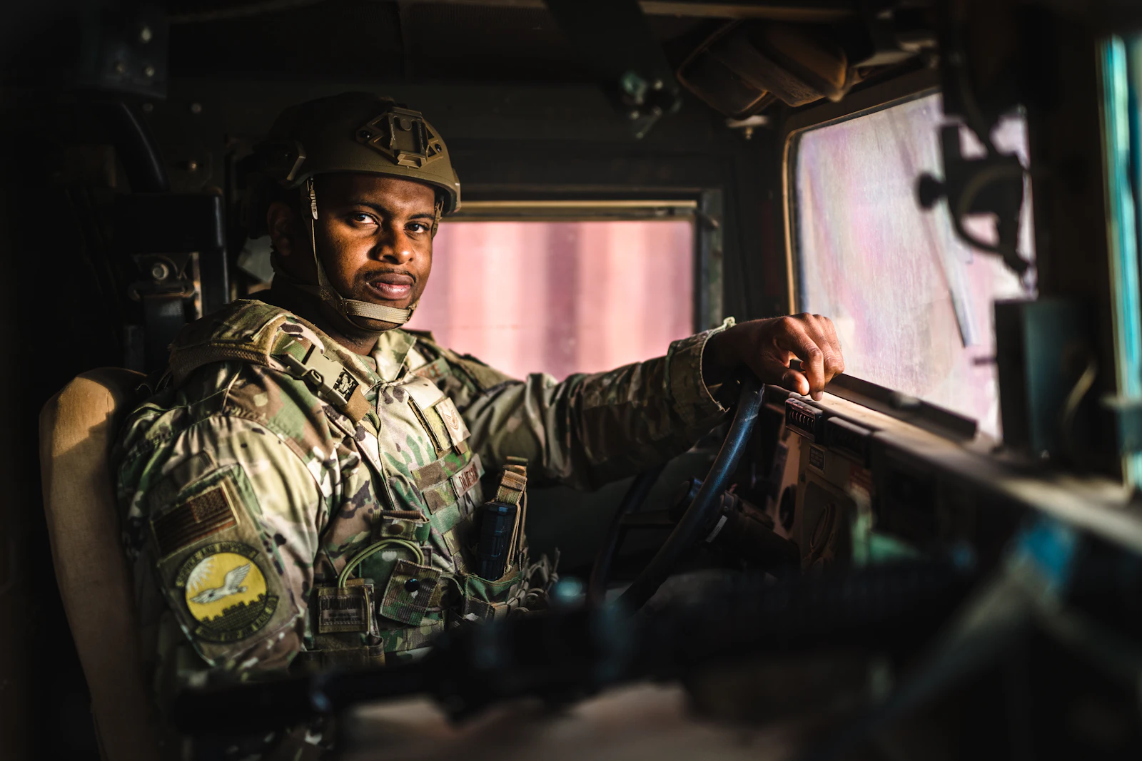 Military service member in uniform sitting inside a military vehicle