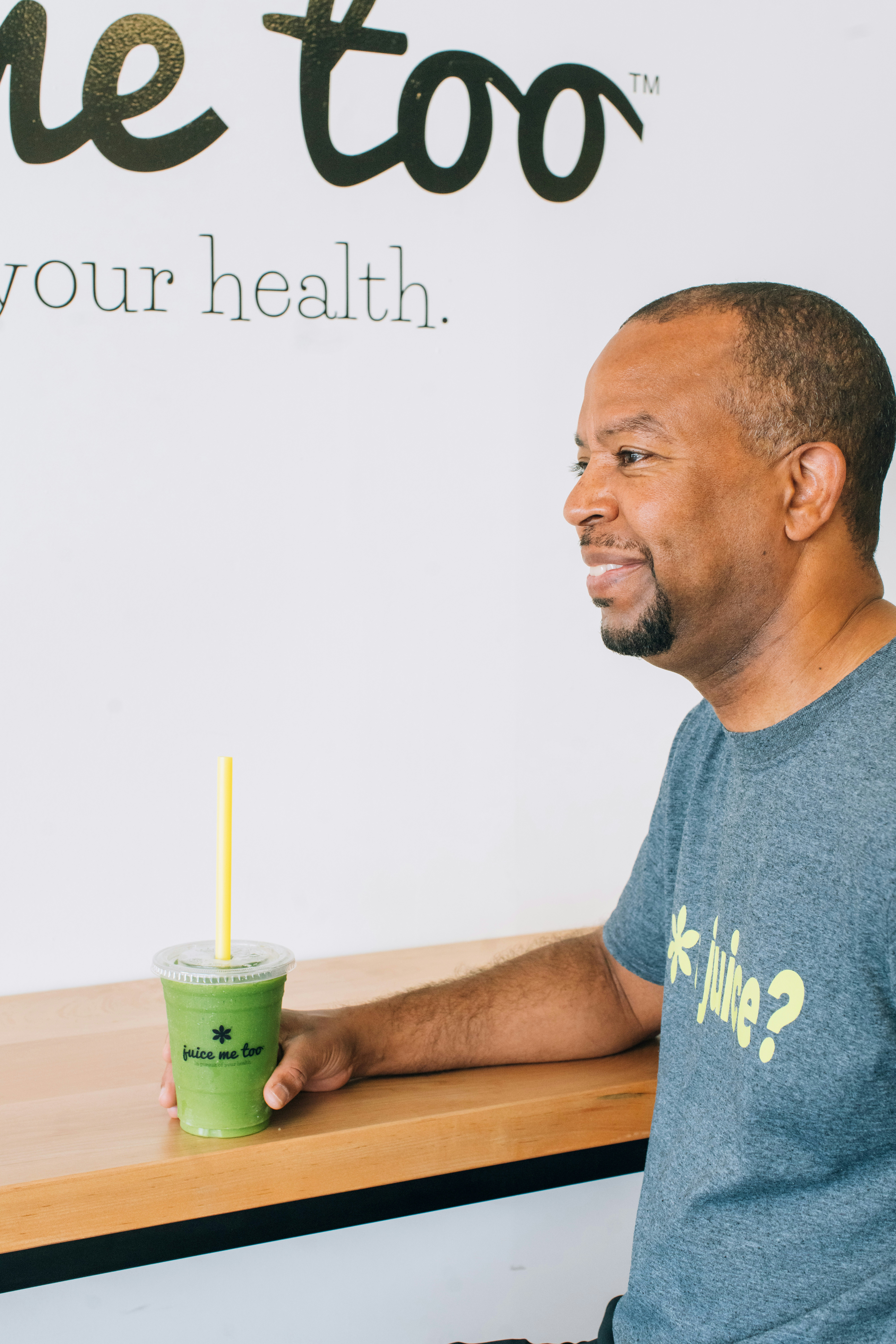 Man smiles while holding a green juice.
