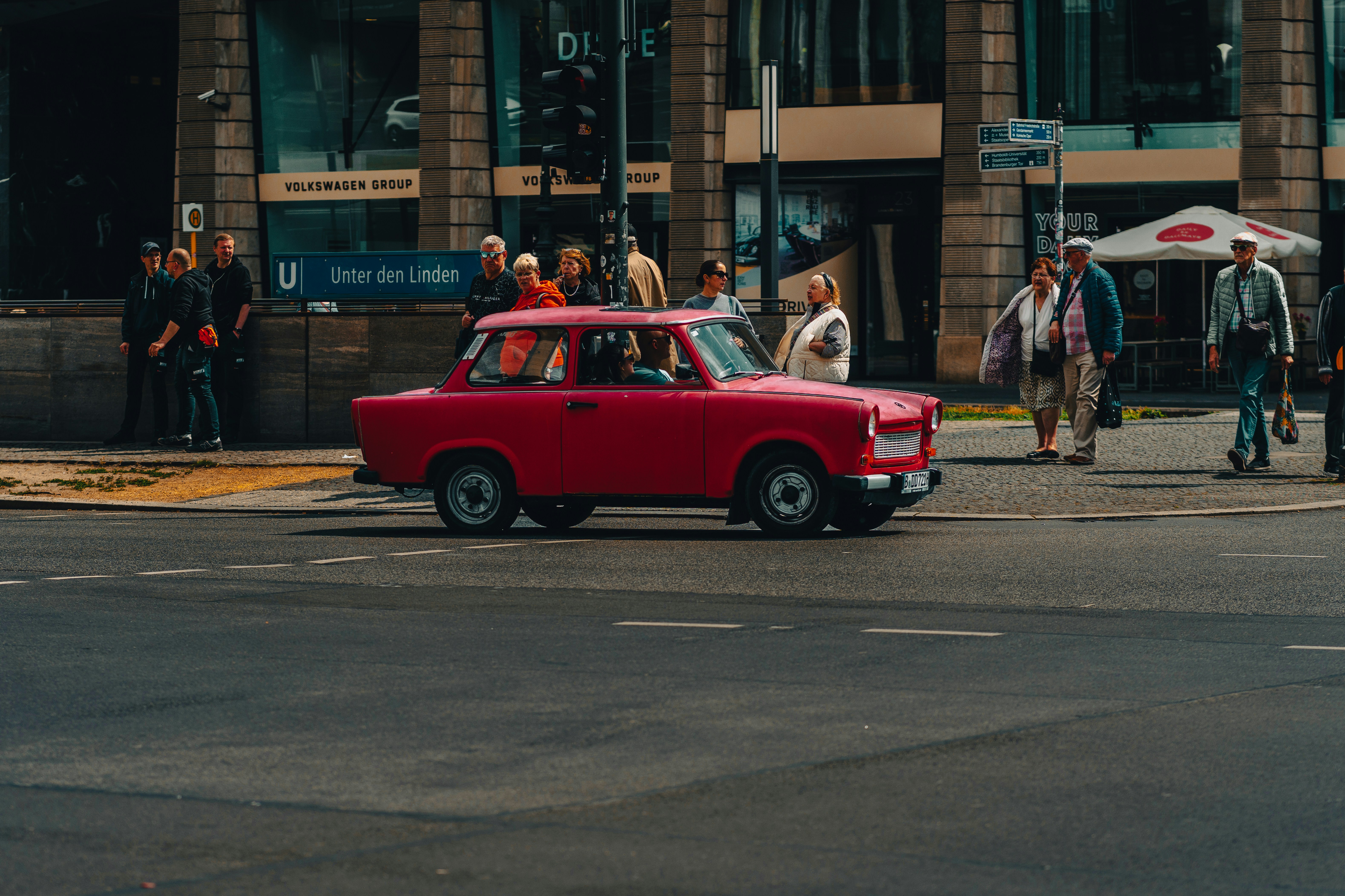 A red car drives through a city street.