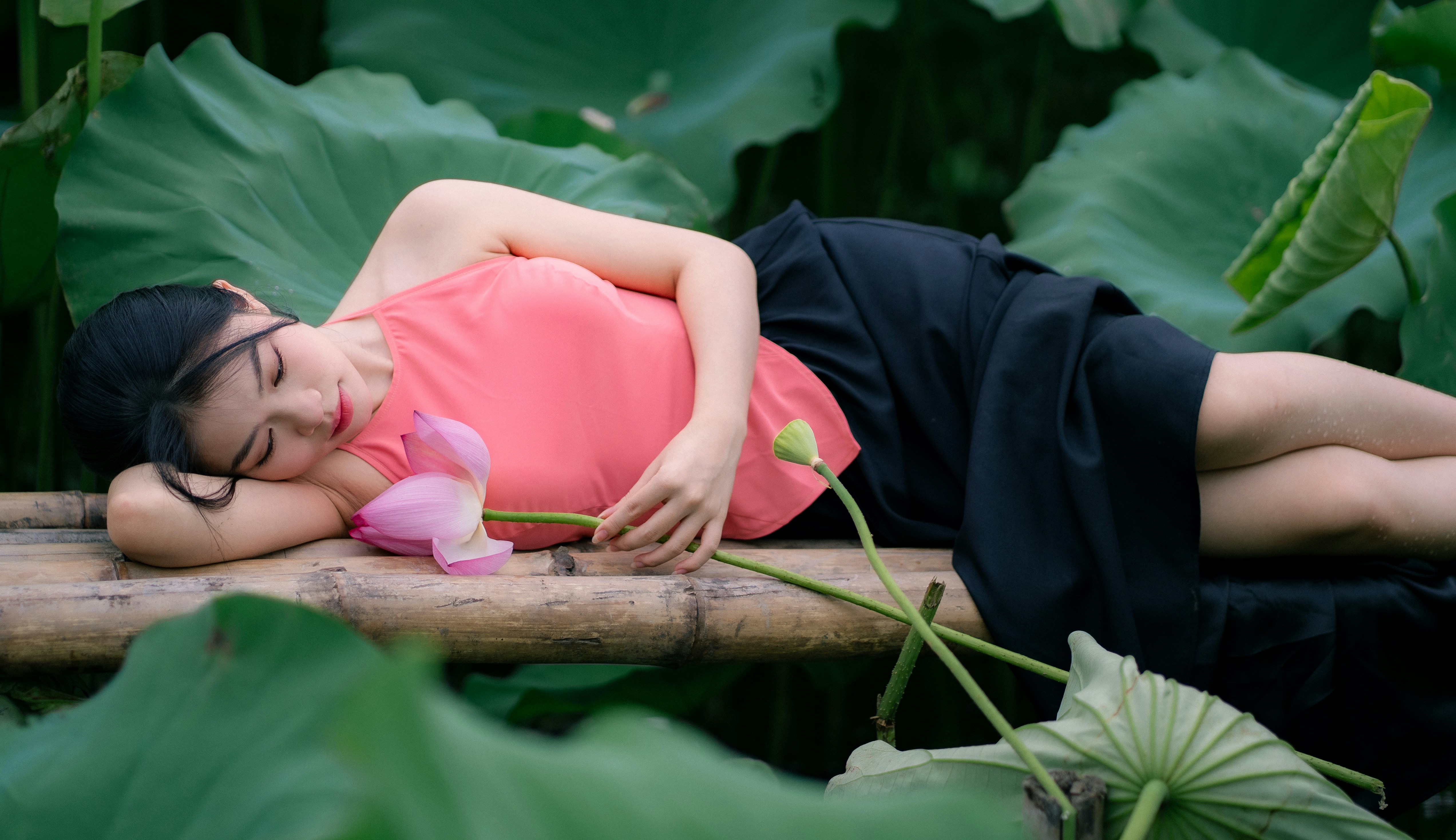 A woman rests beside a lotus flower.