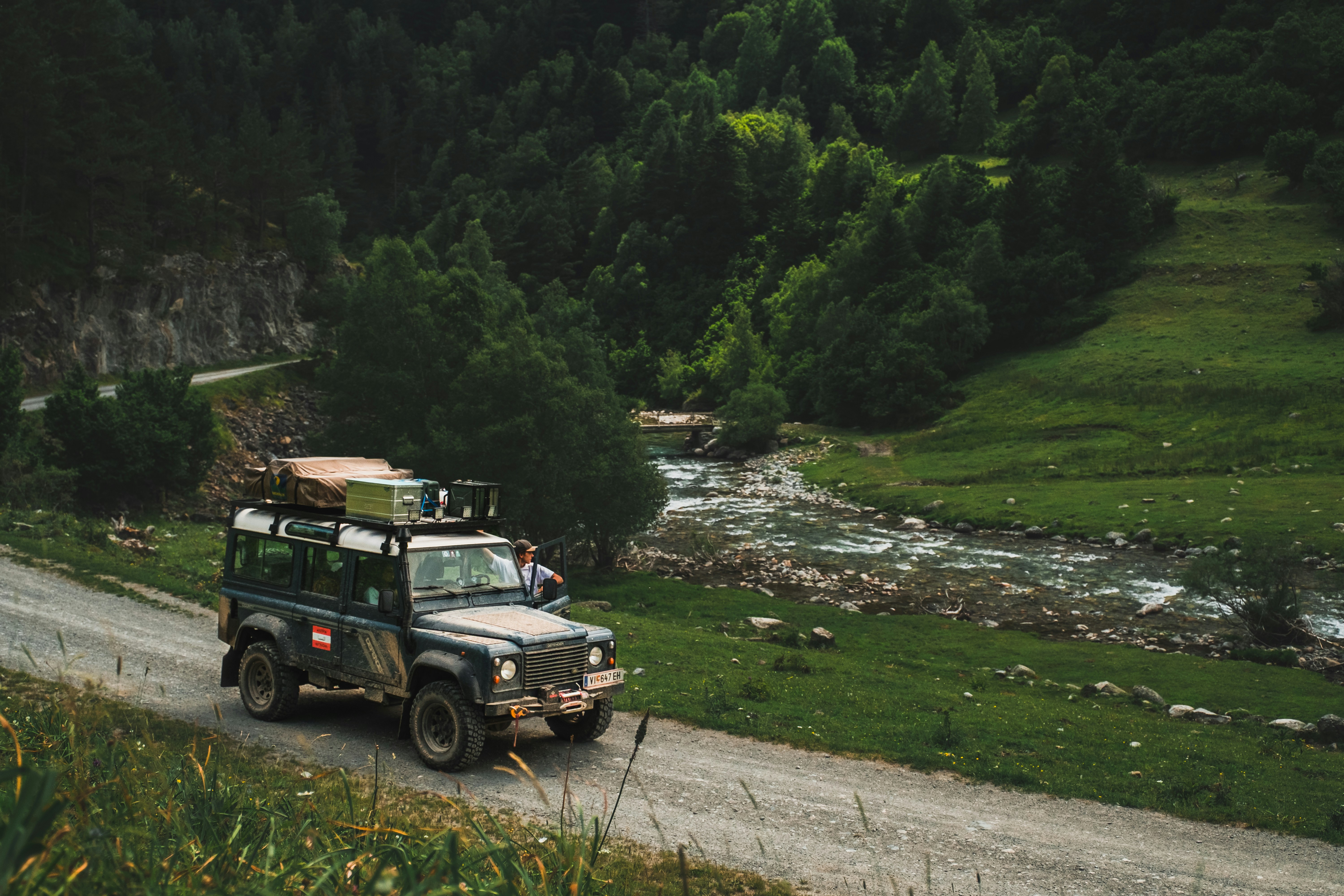랜드로버가 숲 속의 도로를 따라 주행합니다.