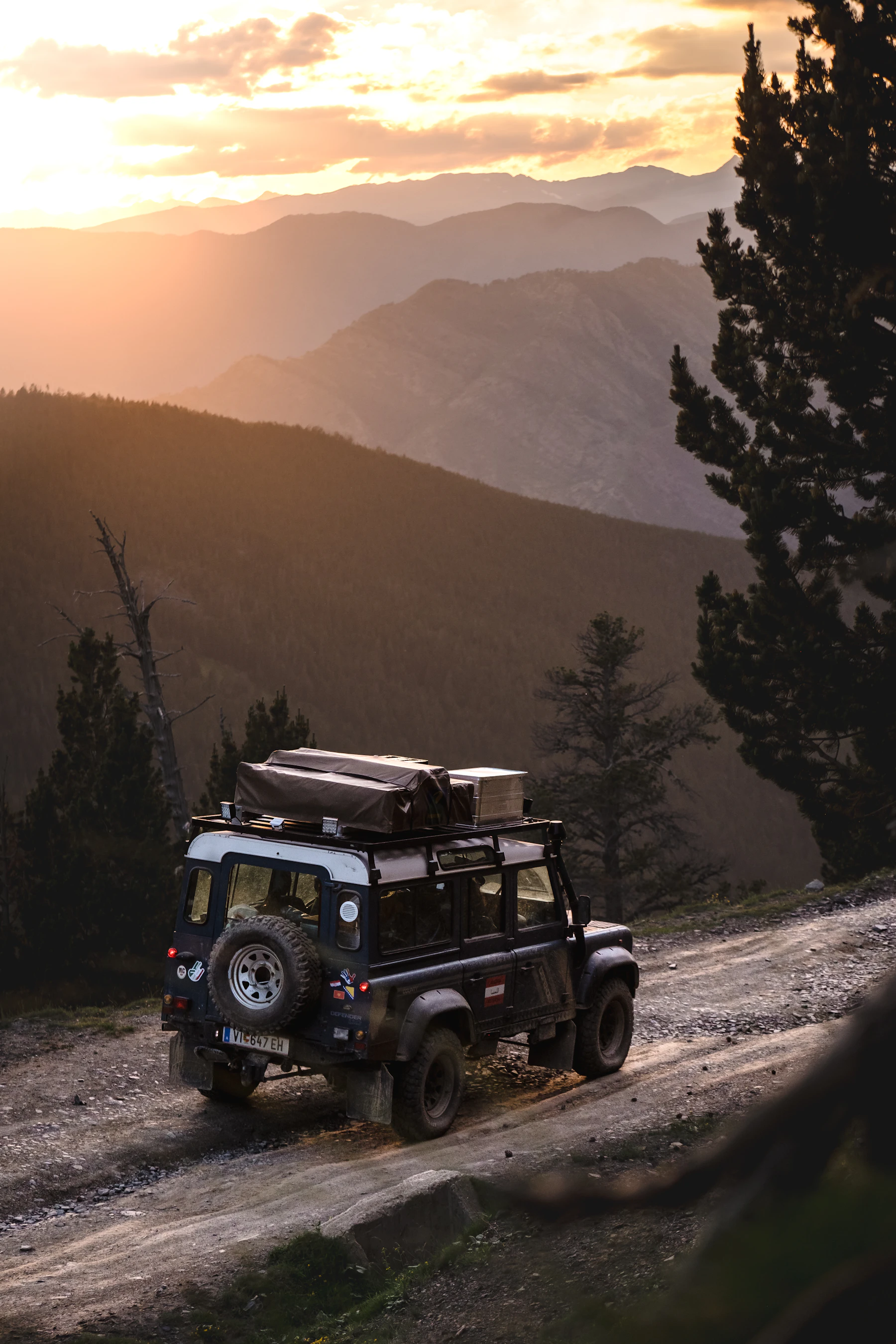 SUV travelling on a mountain road at sunset